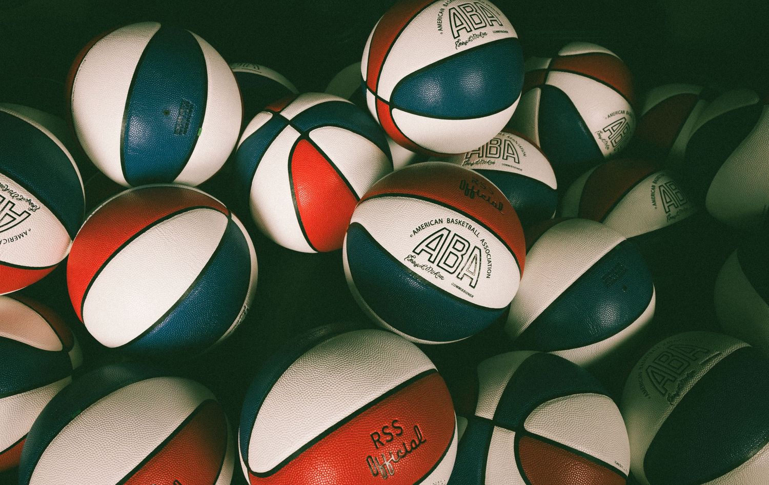 A pile of red, white, and blue ABA basketballs stacked together in a vintage-style photograph.