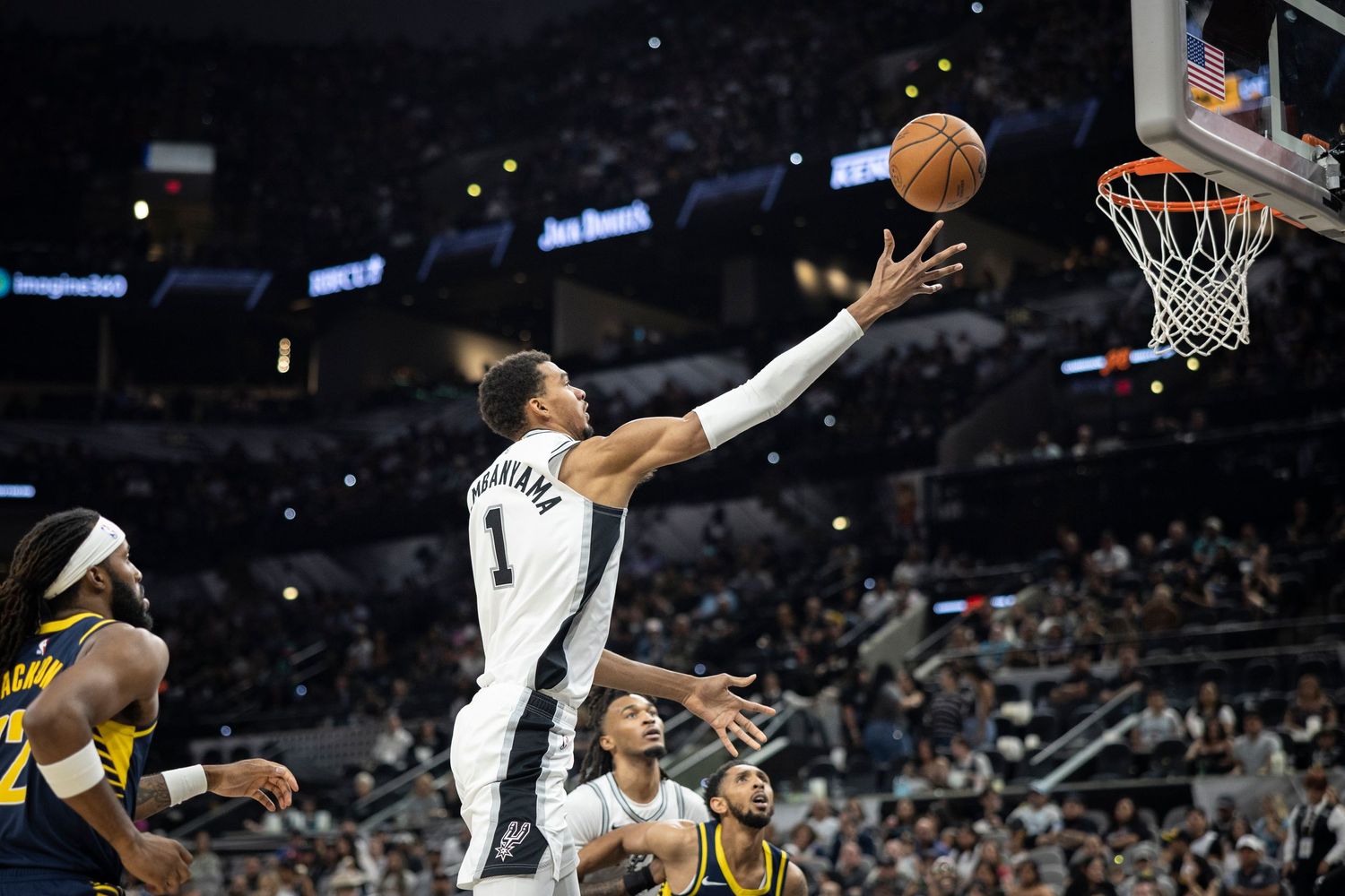 Basketball players battle for possession during a professional game between the Spurs and Pacers.