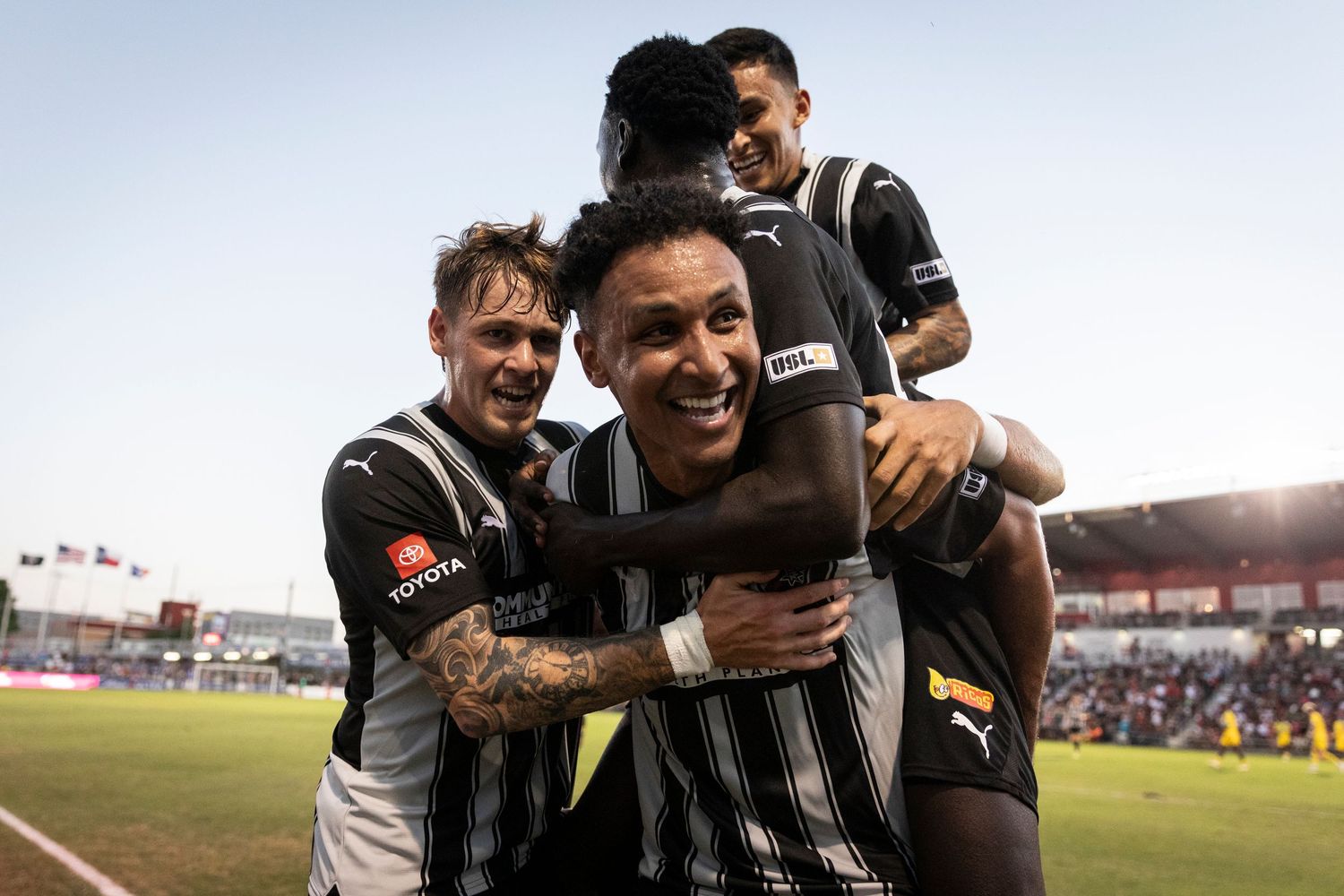 Soccer teammates celebrate together during match in striped uniforms.