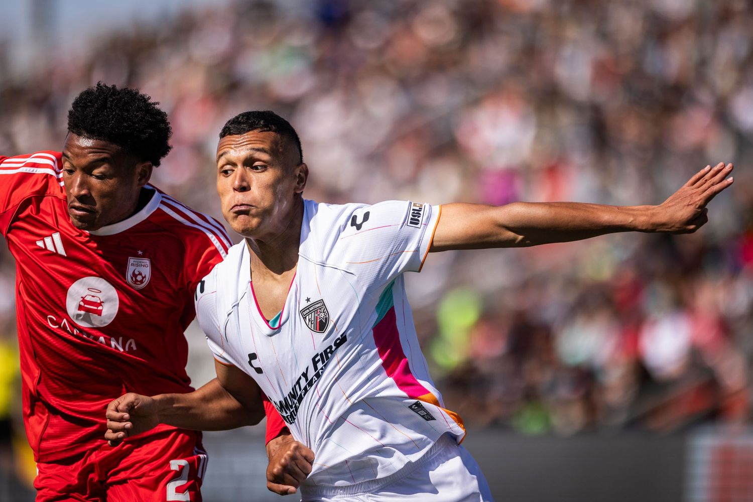 Two soccer players compete for position during competitive match.