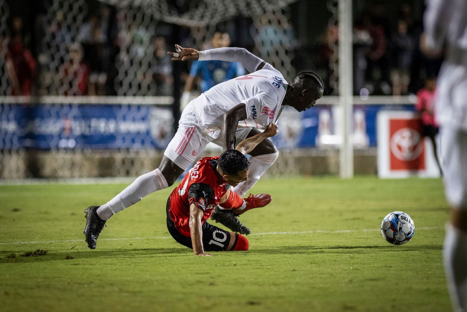 Two soccer players collide while competing for the ball during intense match action.