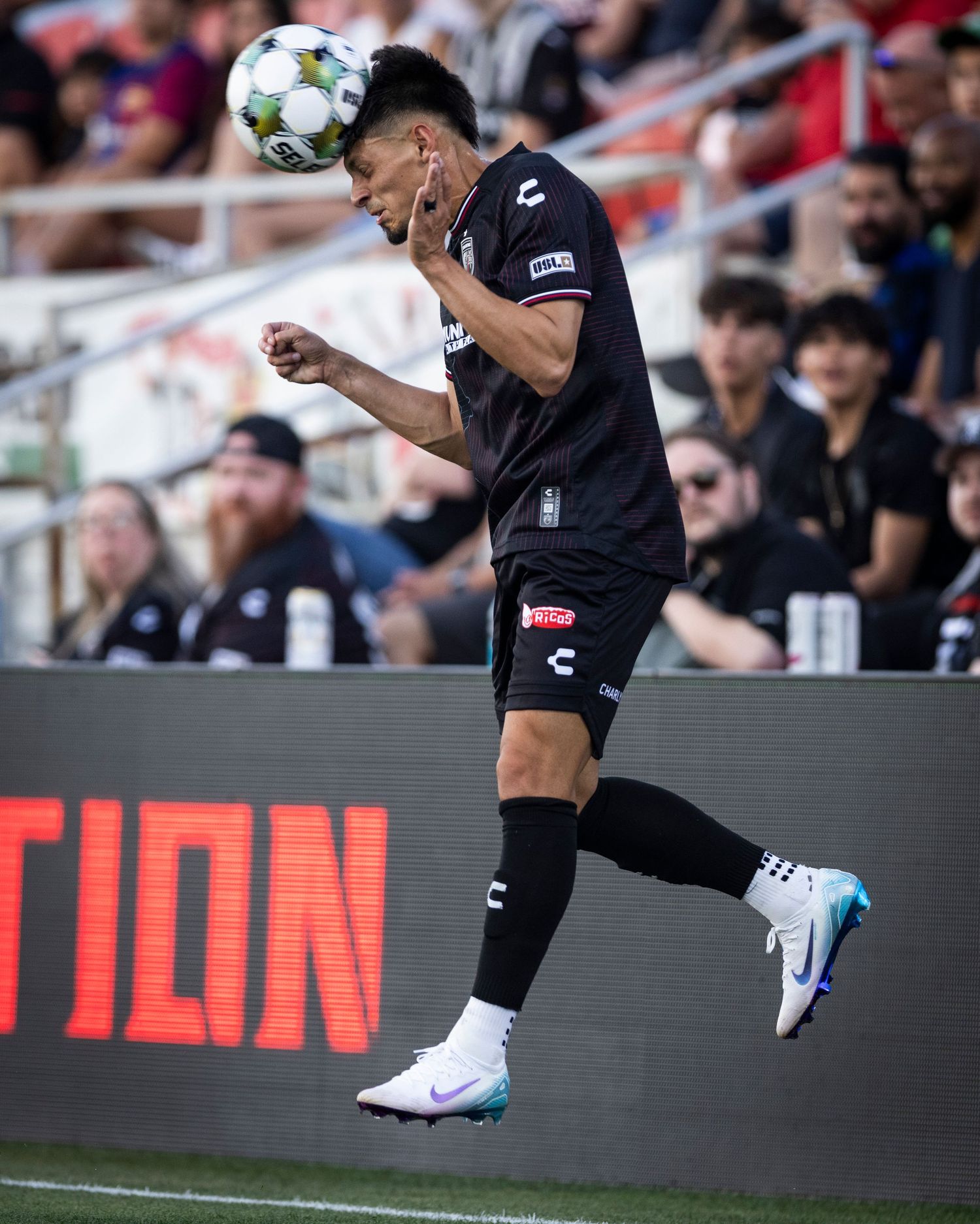 Soccer player jumps high to head the ball during a match.