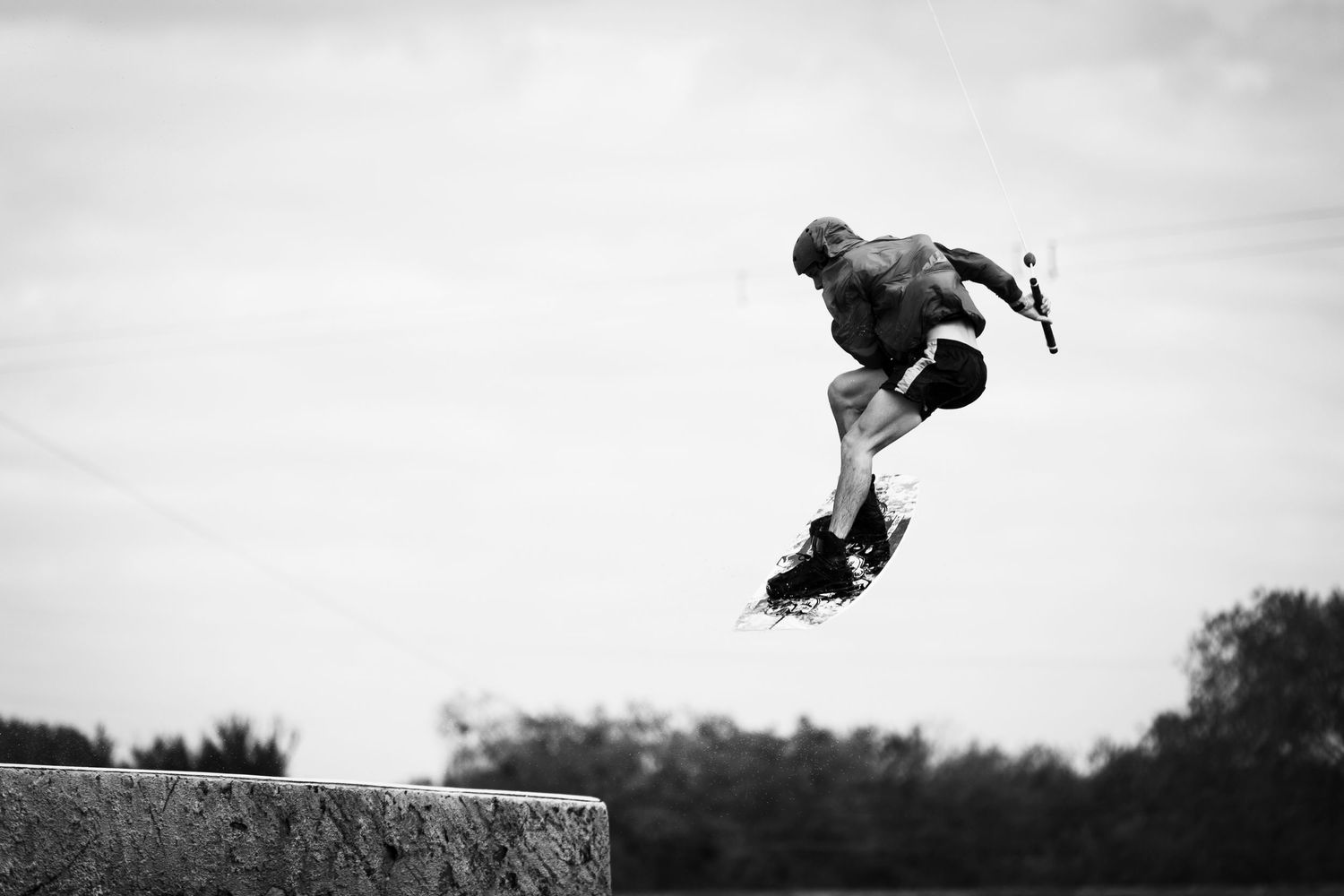 Silhouette of a skateboarder performing an aerial trick off a concrete obstacle.