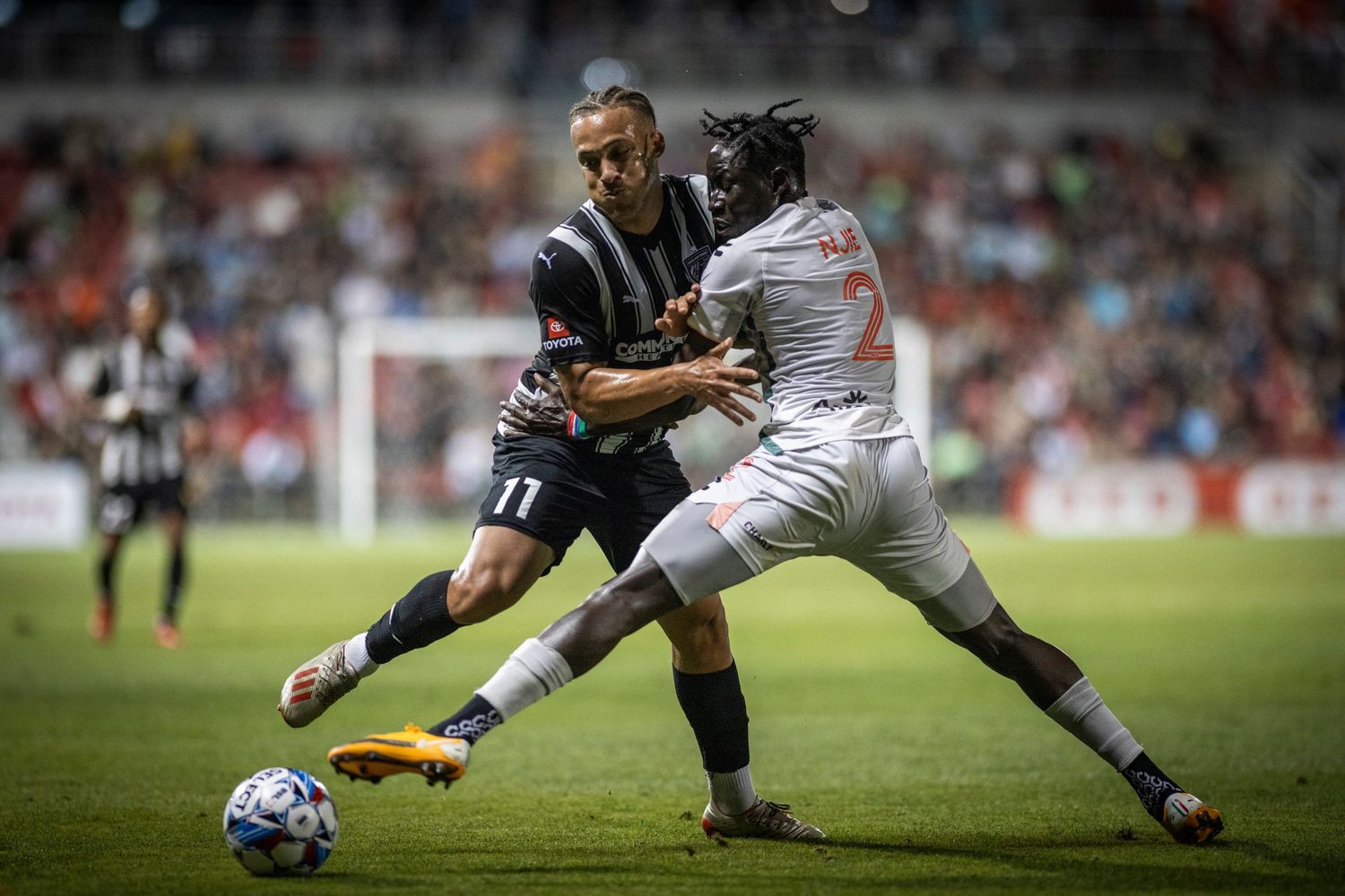 Two soccer players battle for ball possession during competitive match.