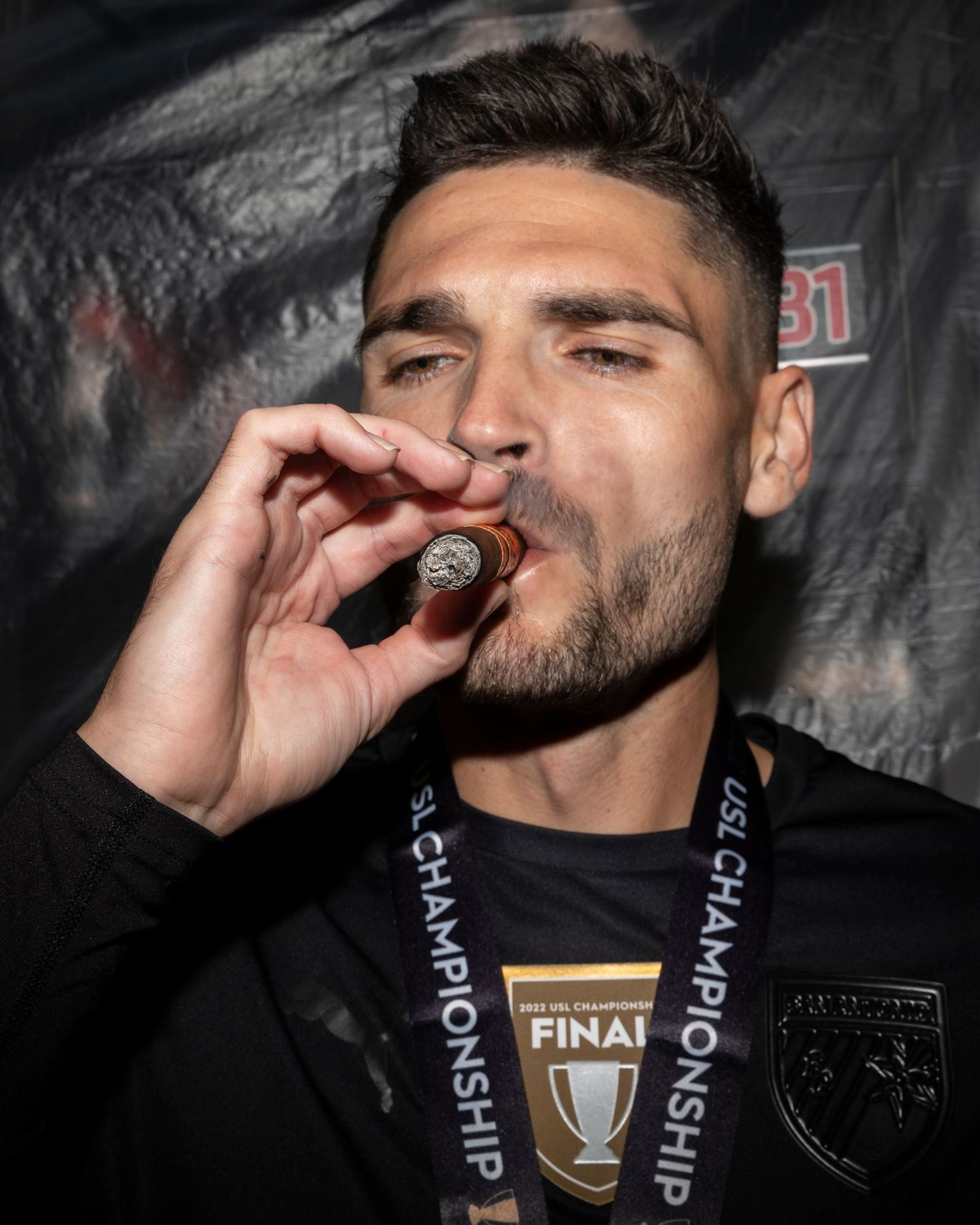 A player celebrates victory with a celebratory cigar while wearing a championship medal.