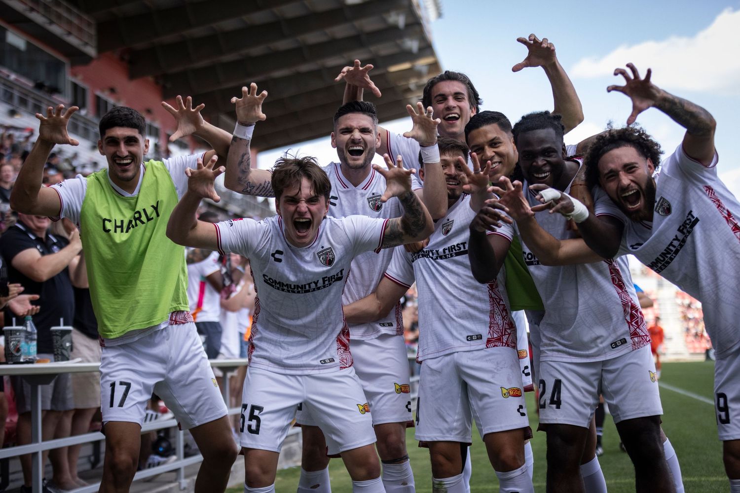 Soccer team celebrates enthusiastically together on the field after a victory.