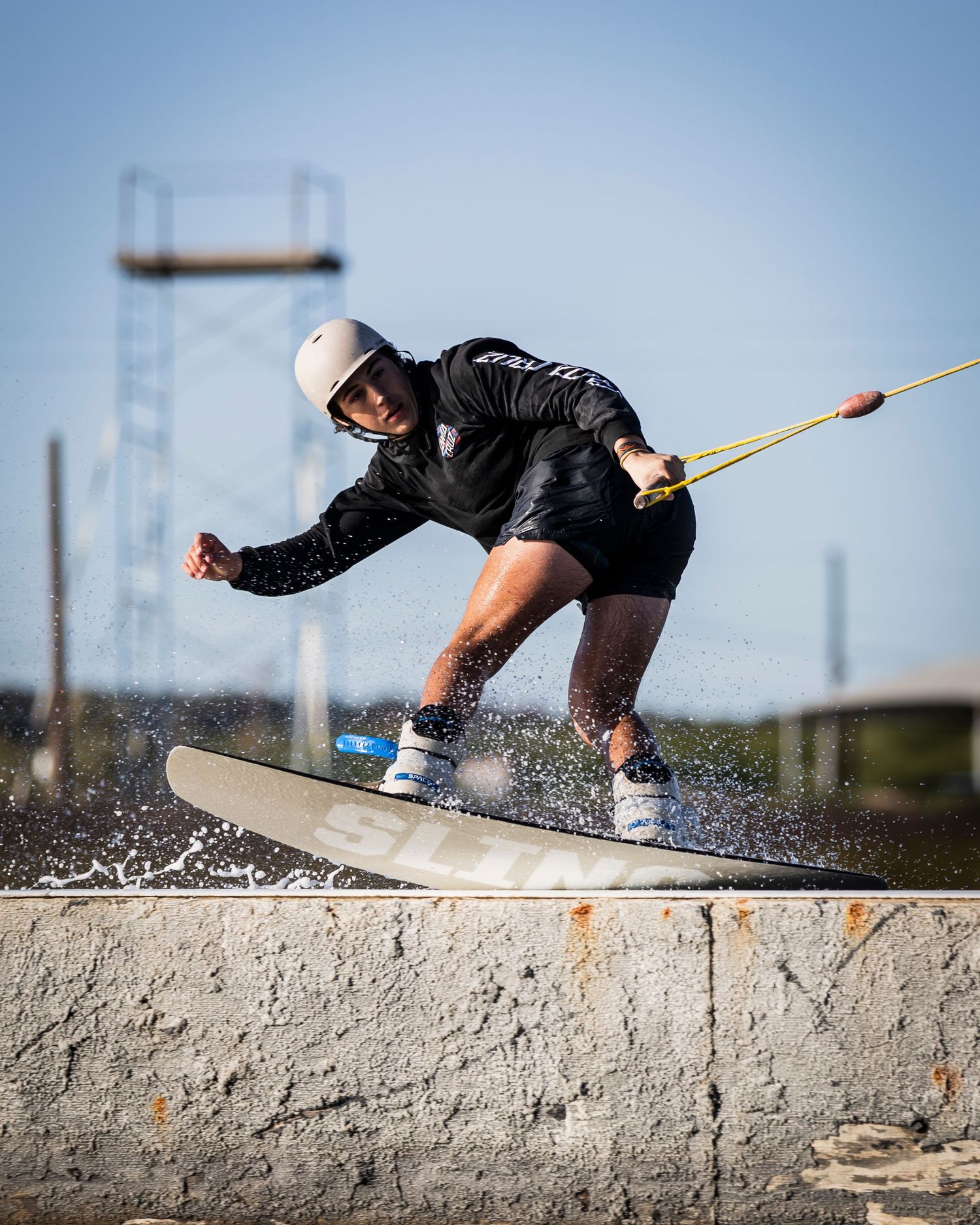 Wakeboarder sliding across concrete obstacle during wakeboarding trick.