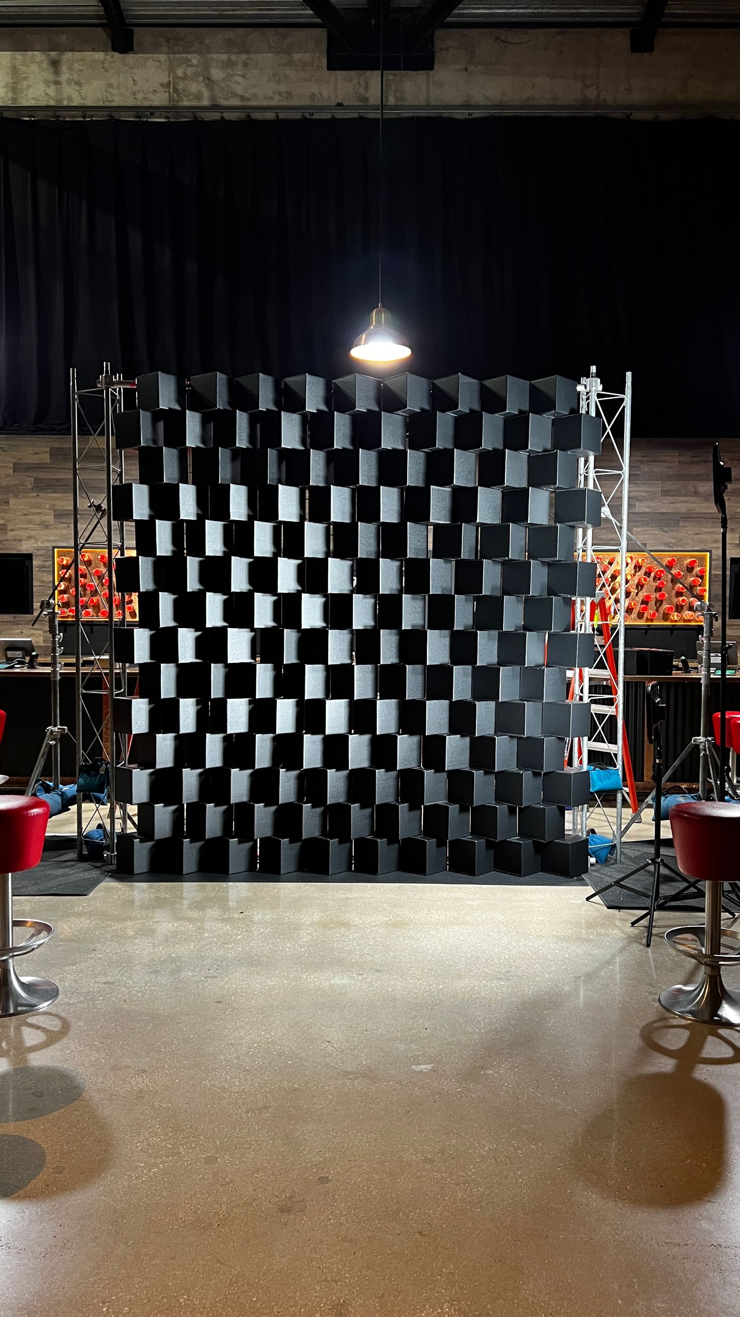 A sequence of four photos showing a studio space with black and white checkered walls and lighting equipment setup.