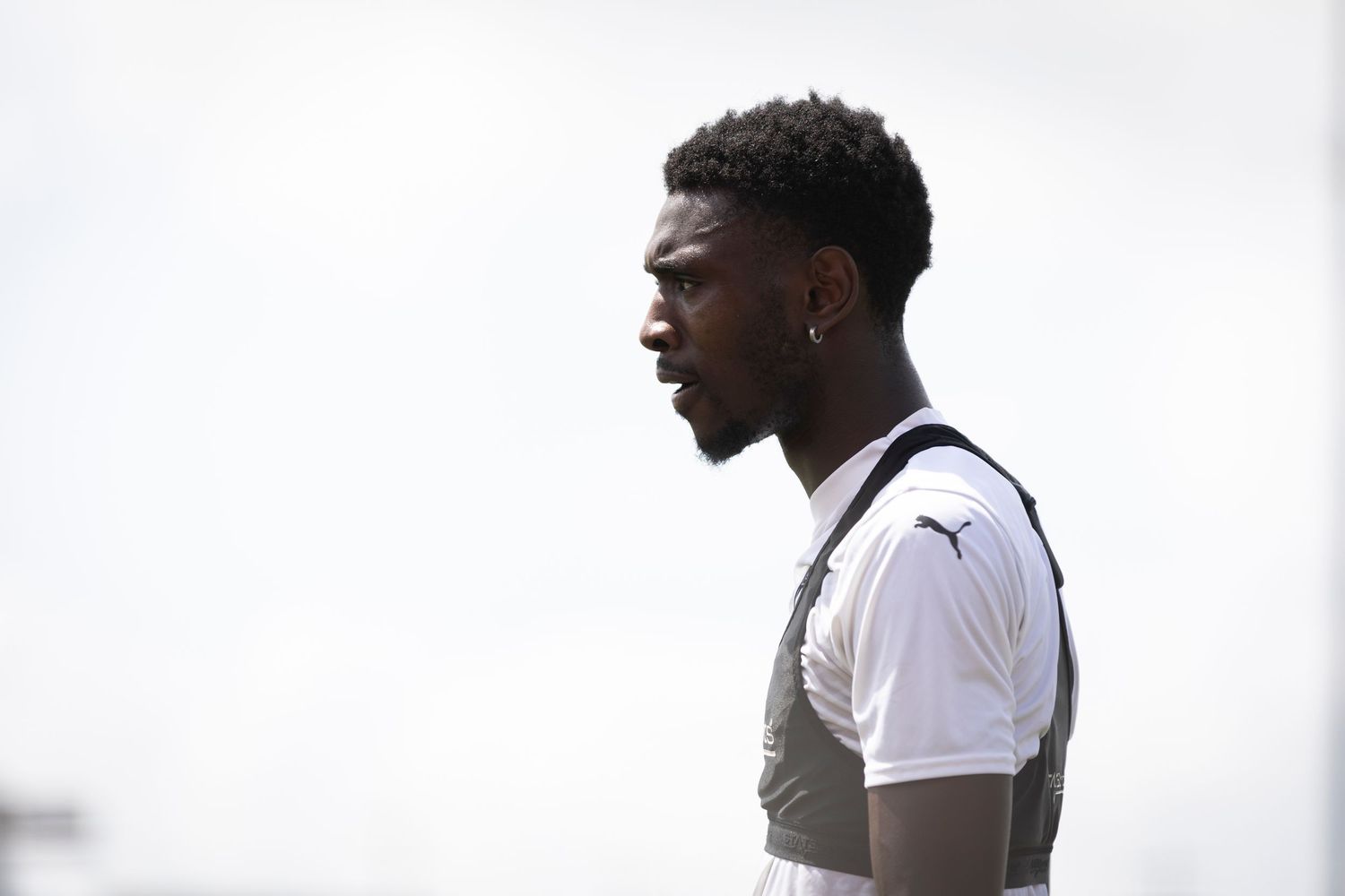 Profile view of athlete in black and white training gear against overcast sky.