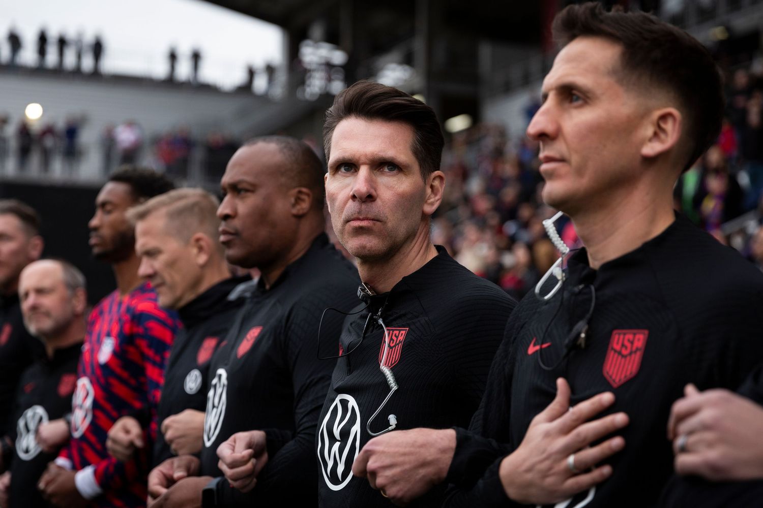 Soccer team members stand at attention during pre-match ceremony at stadium sideline.
