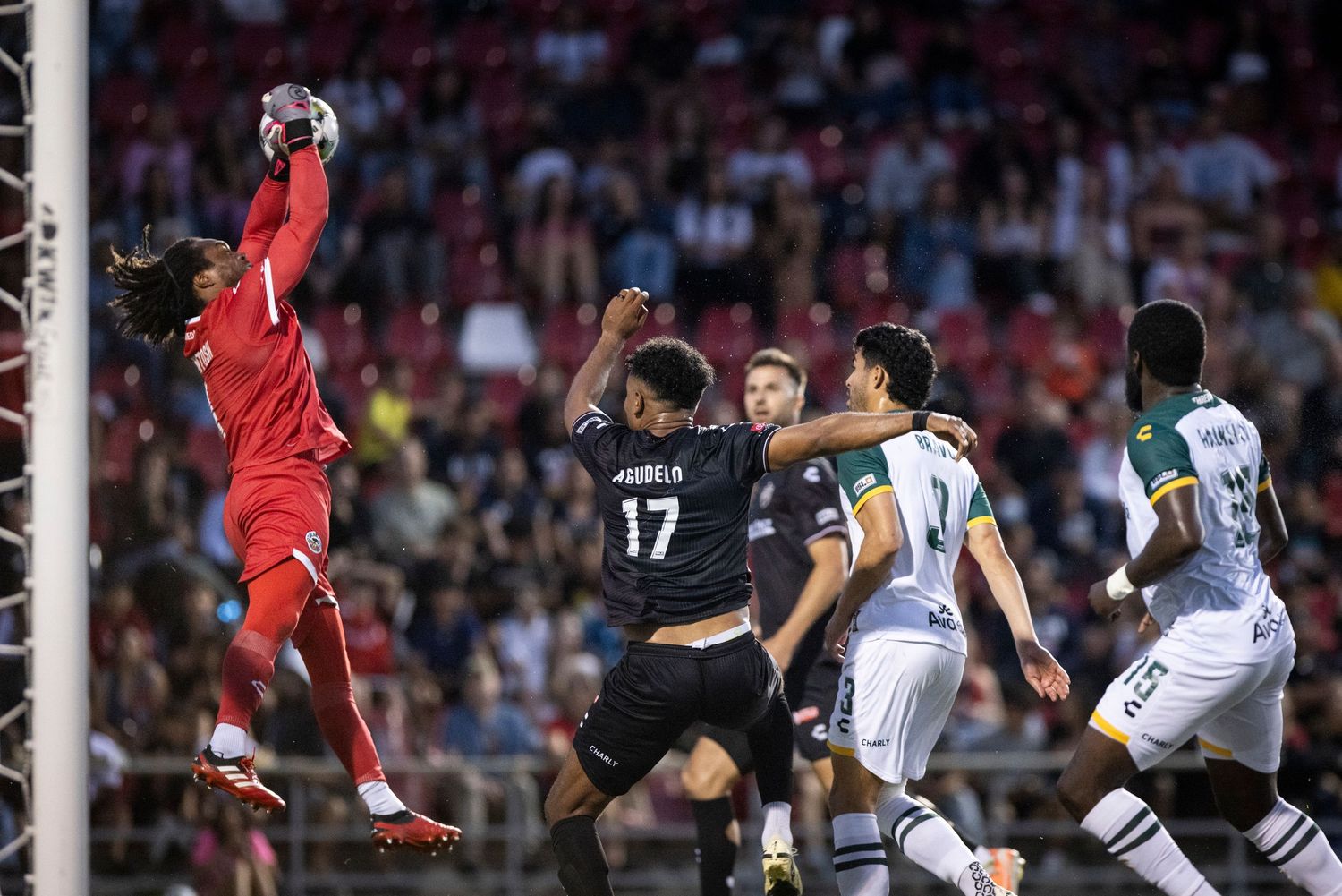 A goalkeeper leaps to make a save during an intense soccer match.