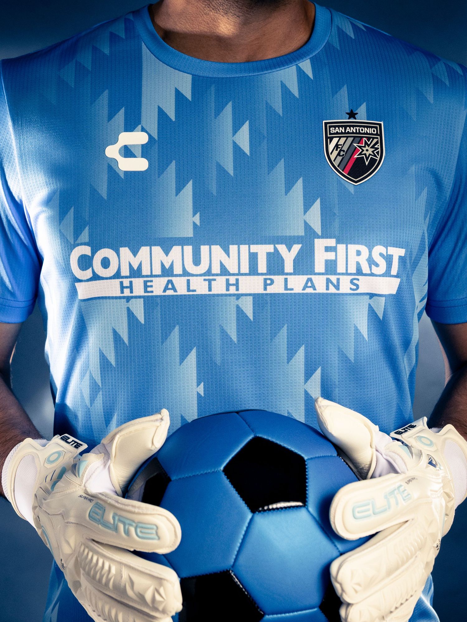 San Antonio FC goalkeeper in blue Charly kit with Community First Health Plans sponsor, holding a soccer ball.