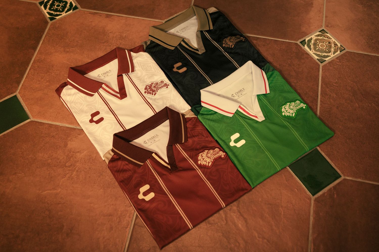 Four folded polo shirts in white, maroon, dark blue, and green with Chivas logo displayed on a tiled floor.