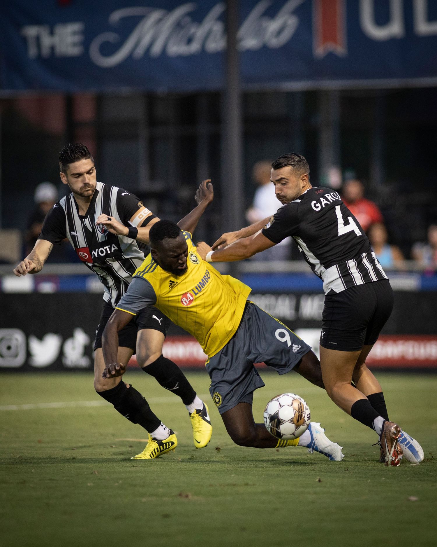 Soccer players battle for possession during intense match action on the field.