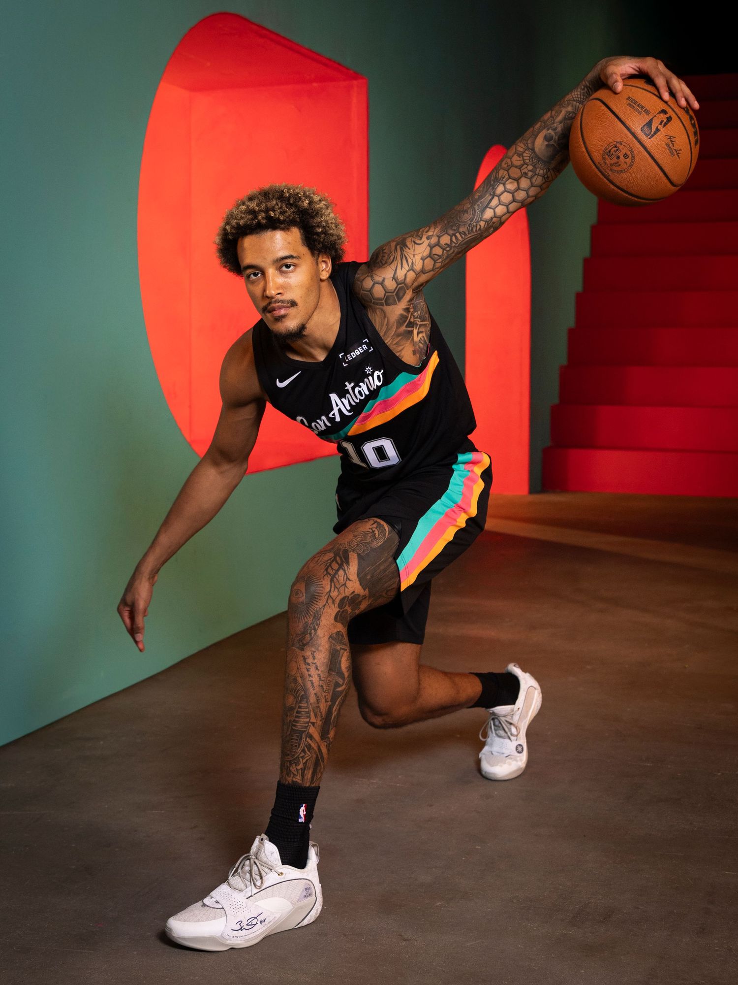 Tattooed basketball player dribbles in a San Antonio Spurs black City Edition Nike uniform.