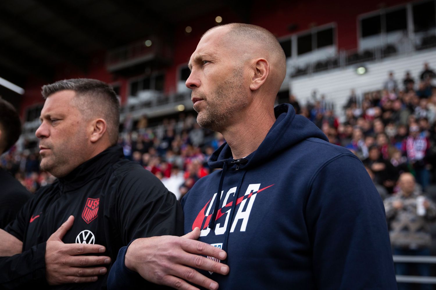 Coaching staff observes from sideline during professional soccer match.