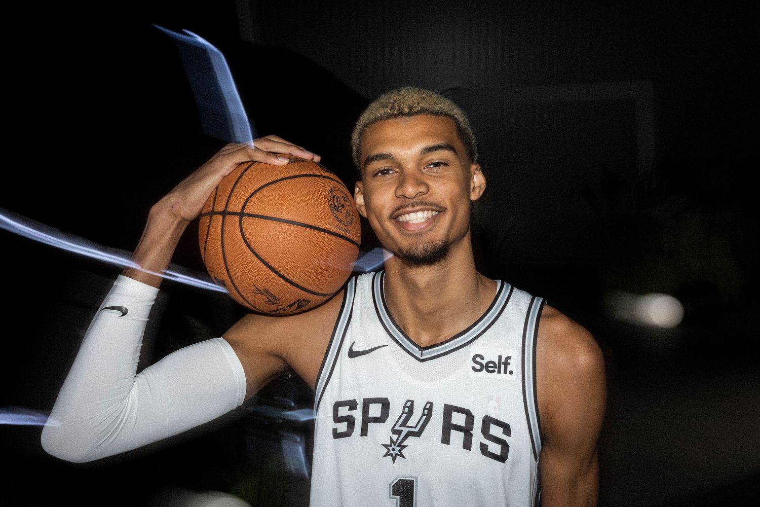 Basketball player in Spurs uniform posing with basketball.