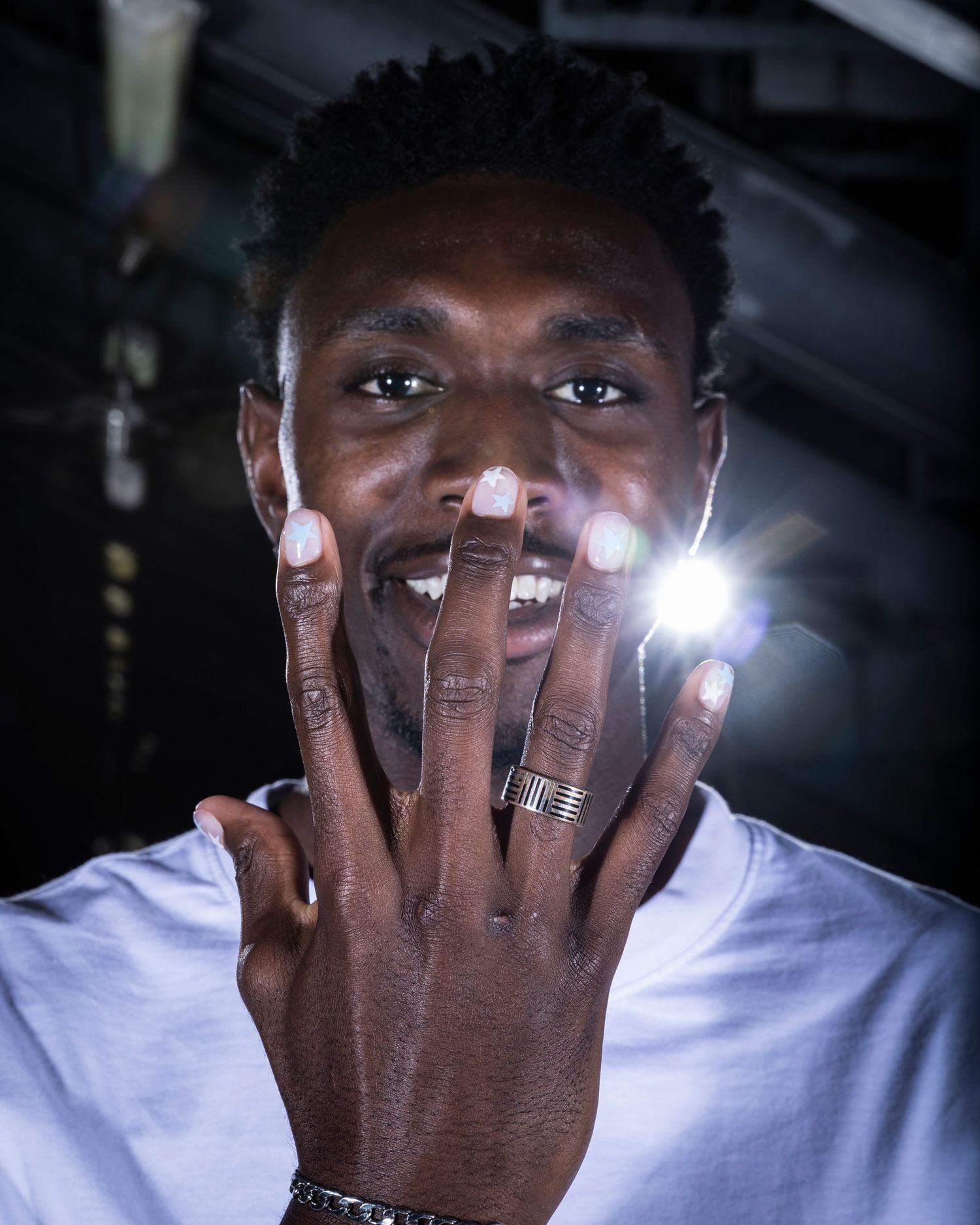 Person wearing white shirt holds bright lights between fingers in artistic photo sequence.