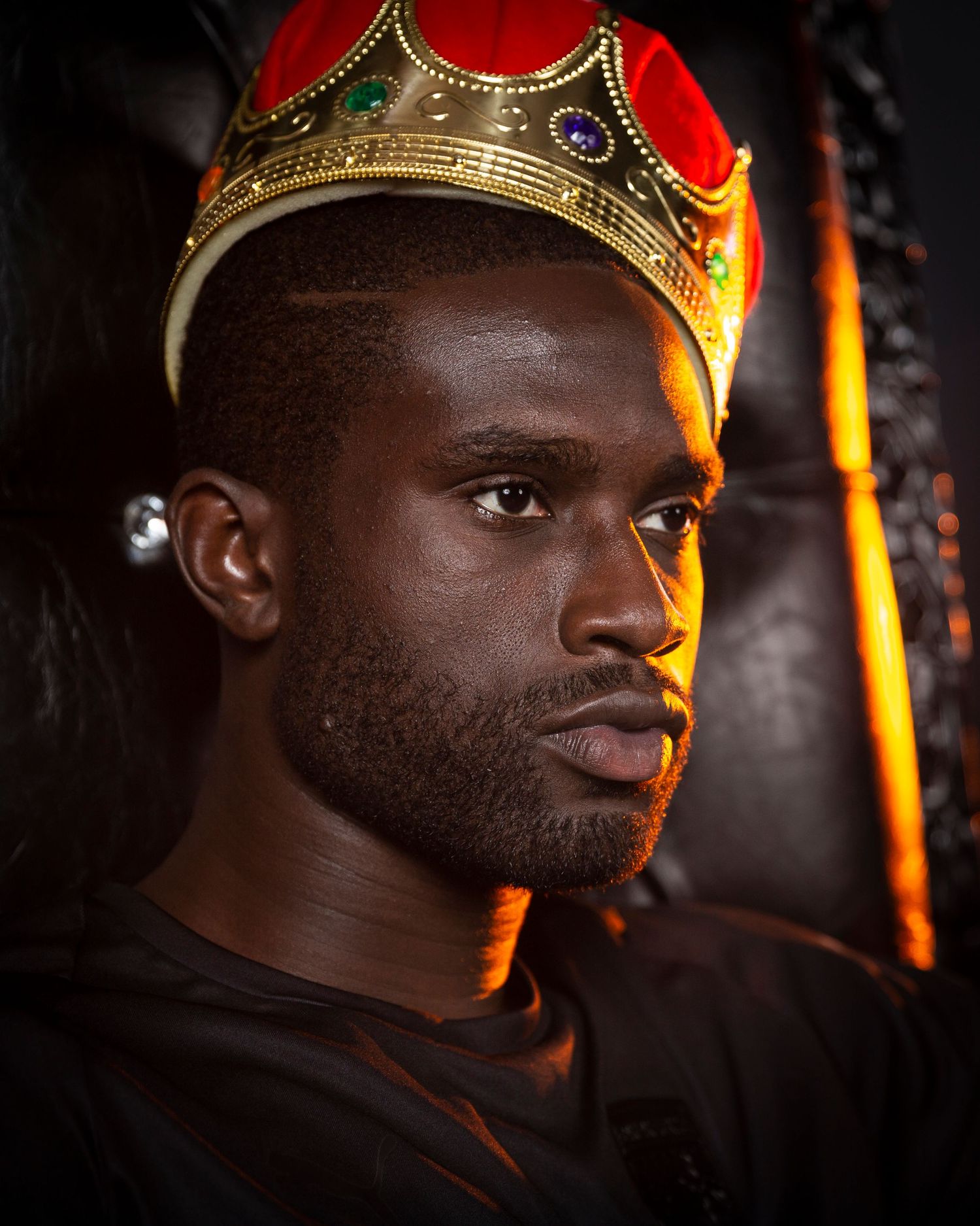 Portrait of athlete wearing gold crown against dark background with dramatic lighting.