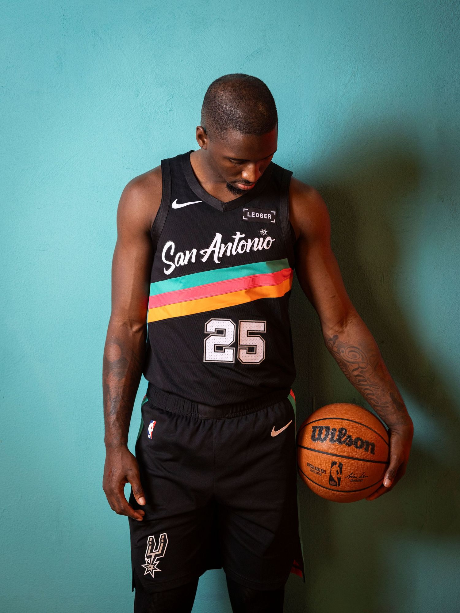 San Antonio Spurs player wearing black Nike jersey number 25 holding a Wilson basketball during media day.