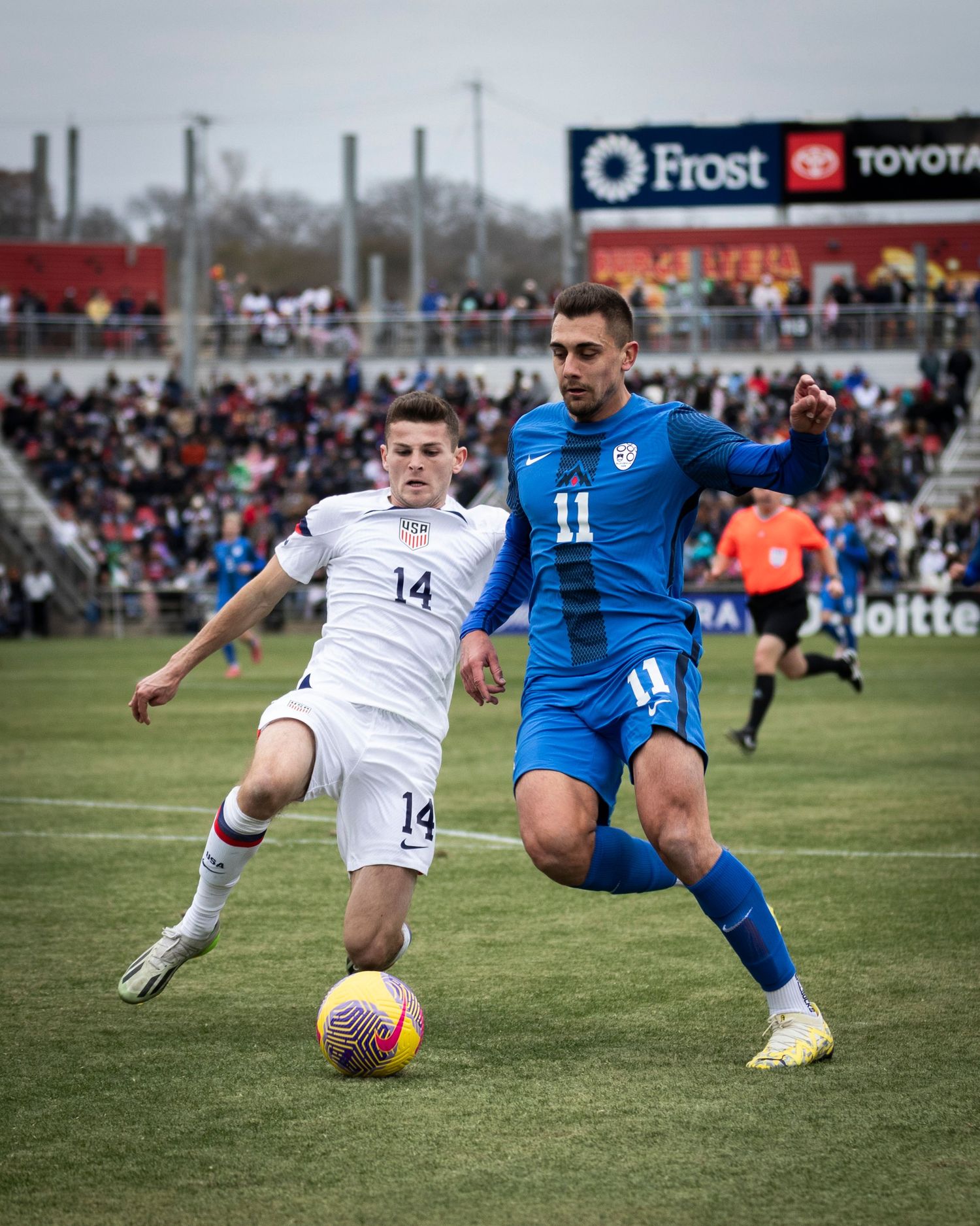 Two soccer players compete for ball possession during international match.