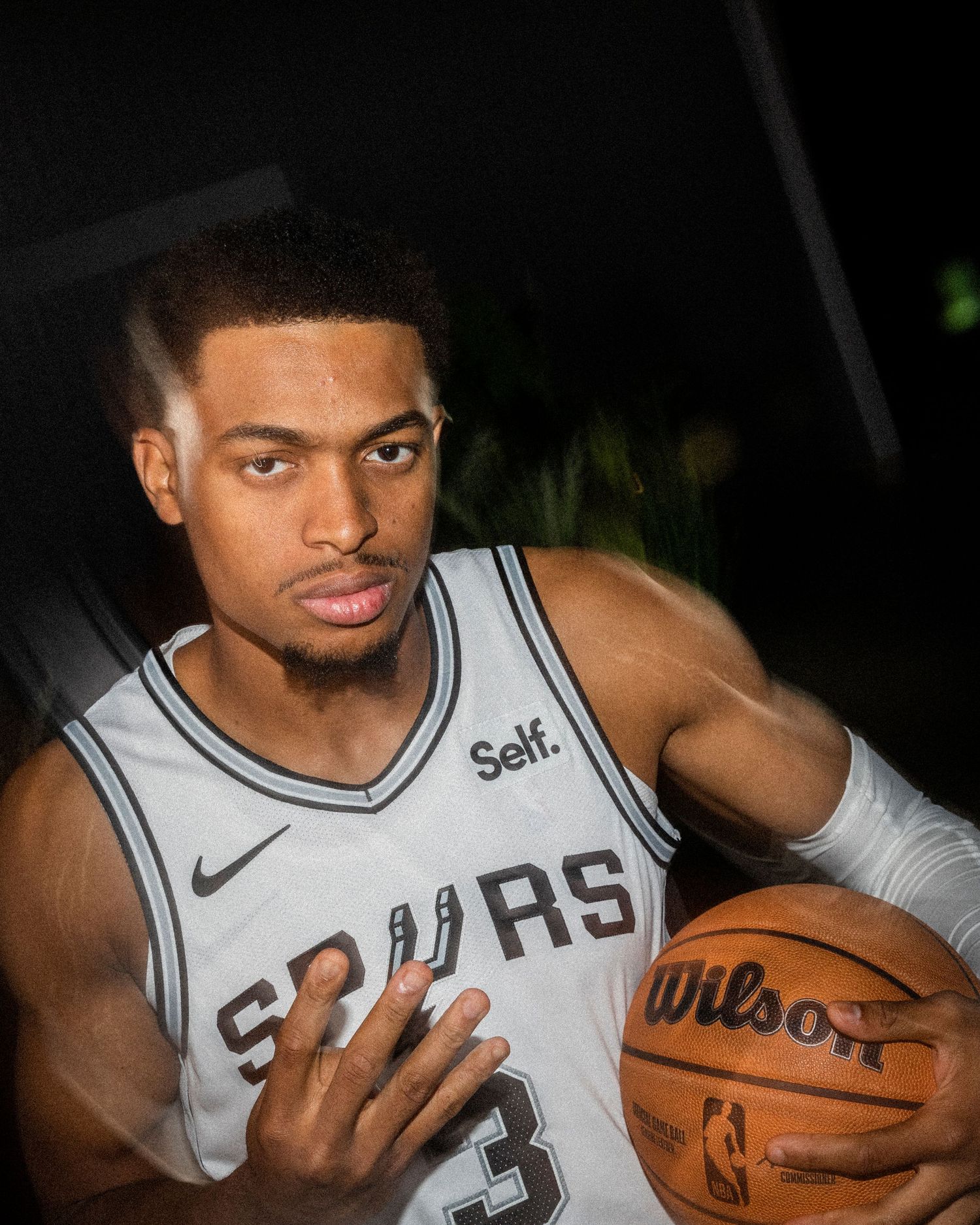 Spurs player number 3 holds Wilson basketball in professional studio portrait.