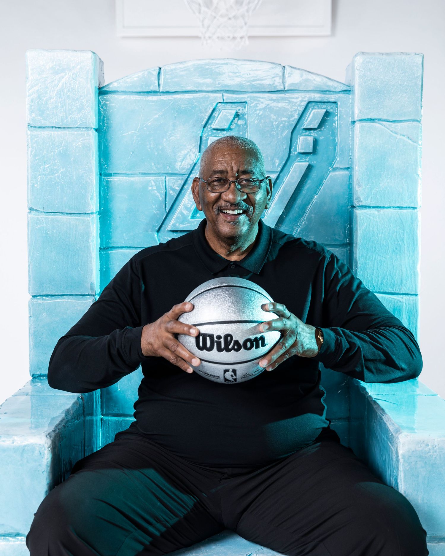 Joyful portrait with Wilson basketball against ice blue backdrop.