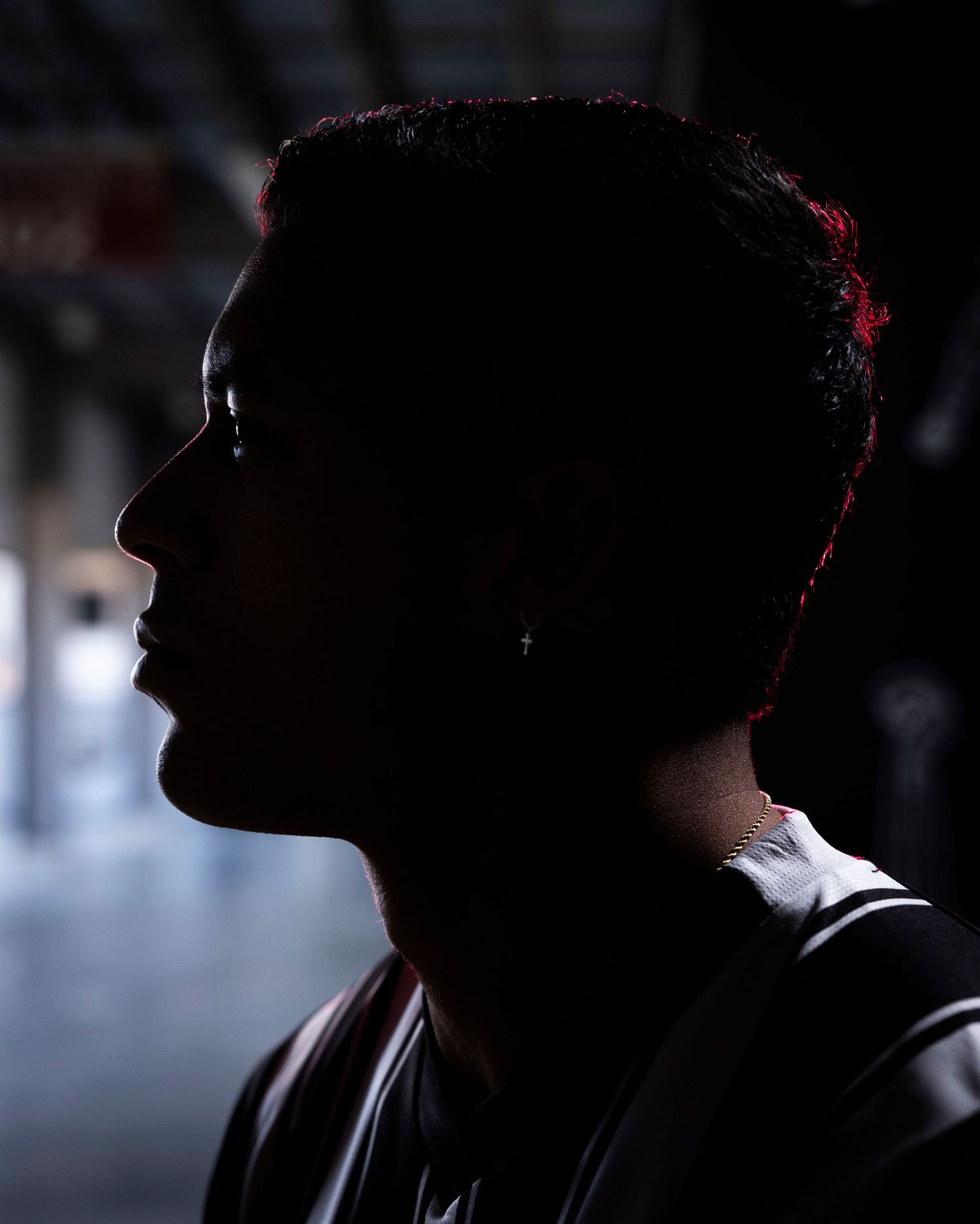 Silhouetted profile portrait of athlete with dramatic red lighting.