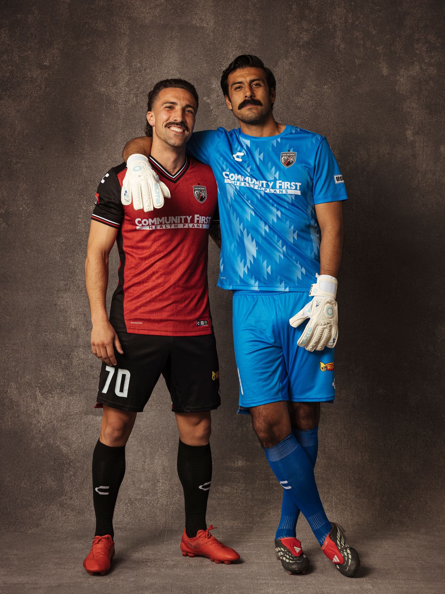 Two soccer players in red and blue Chupacabras uniforms posing together for a team portrait.