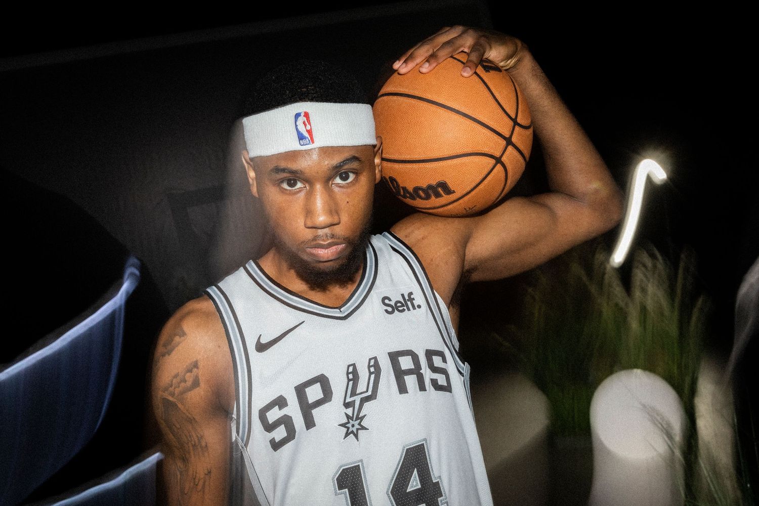 Basketball player in Spurs jersey holding ball with dramatic lighting.