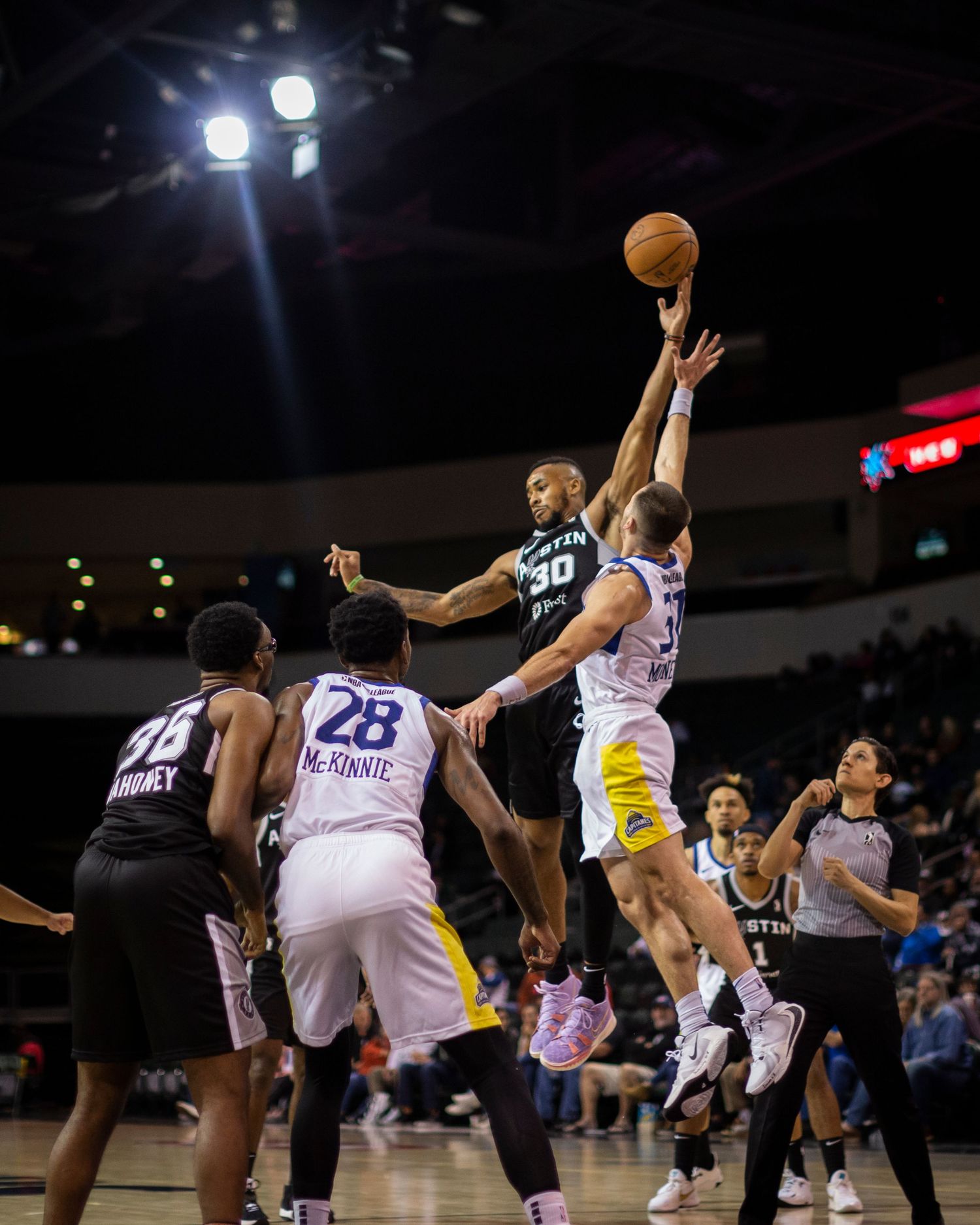 Basketball players jumping for the ball during an intense game action shot.