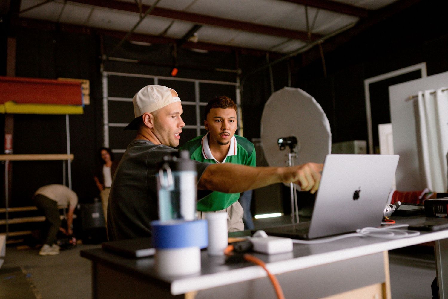 Two people collaborate at a desk while working on laptops in a modern office space.