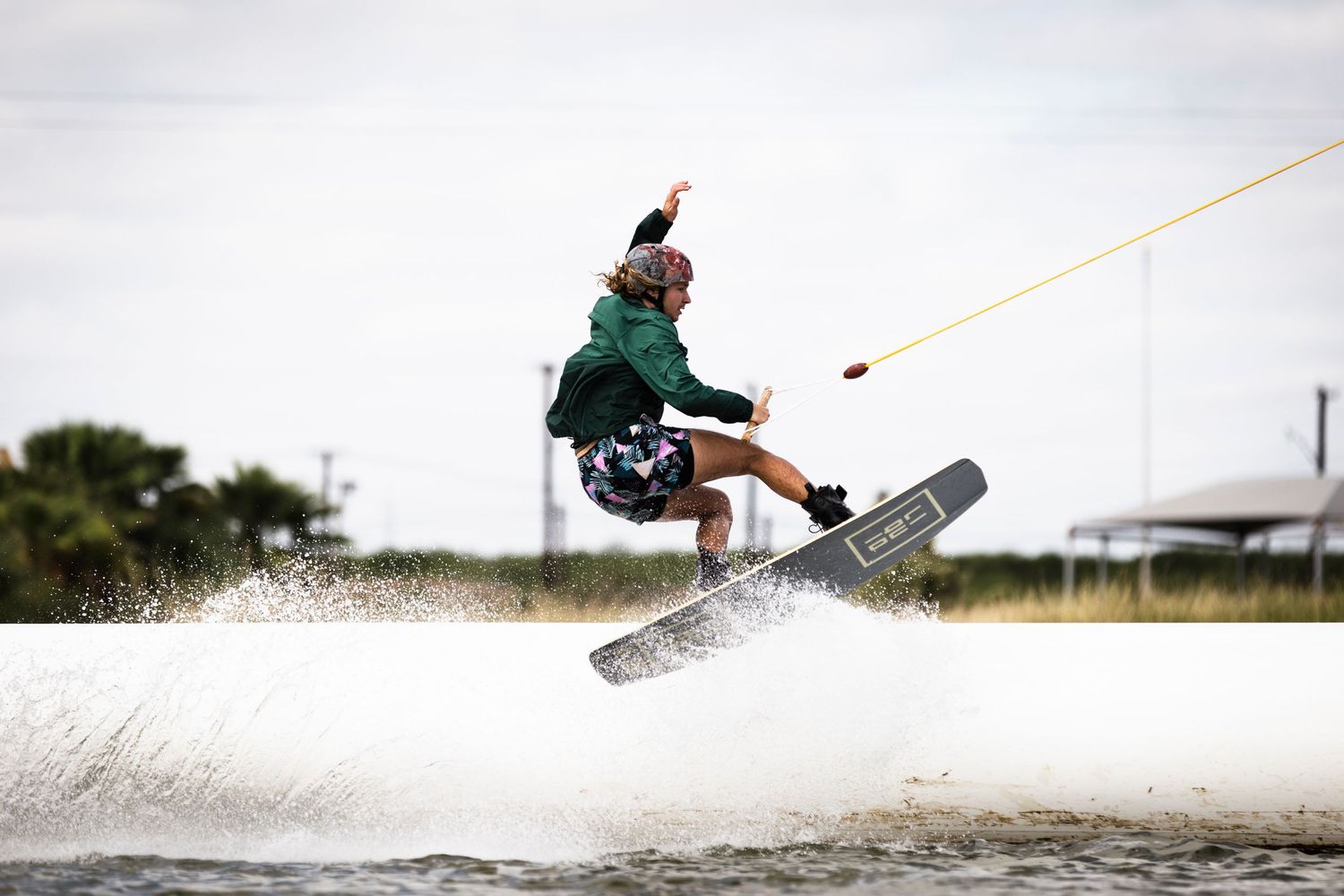 Wakeboarder performs aerial trick during sunset with dramatic water spray.