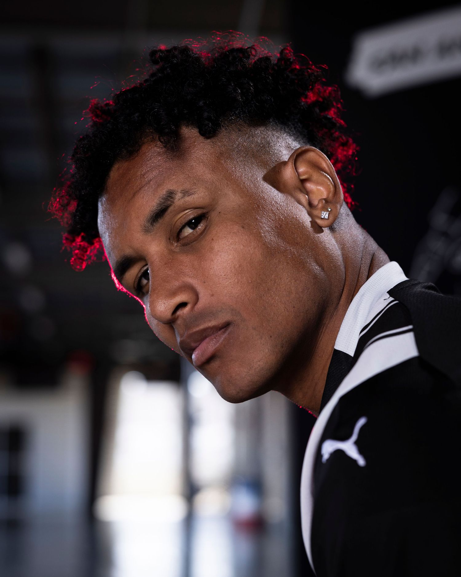 Professional athlete in striped jersey with red-tinted hair and earring in dramatic lighting.