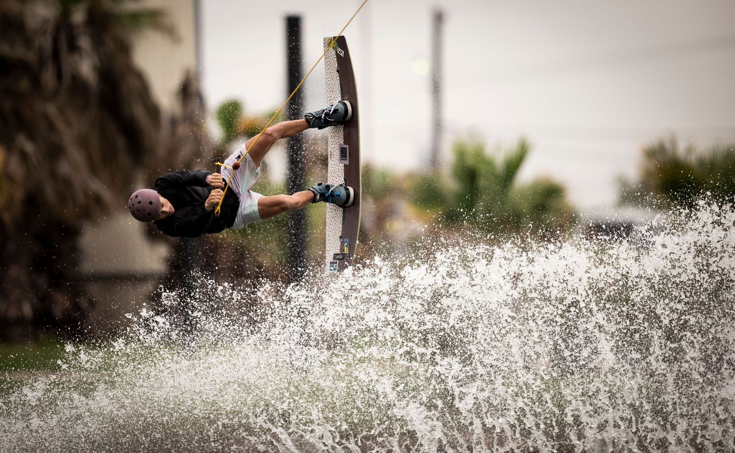 Professional wakeboarder executes a high-speed inverted maneuver creating a dramatic splash.