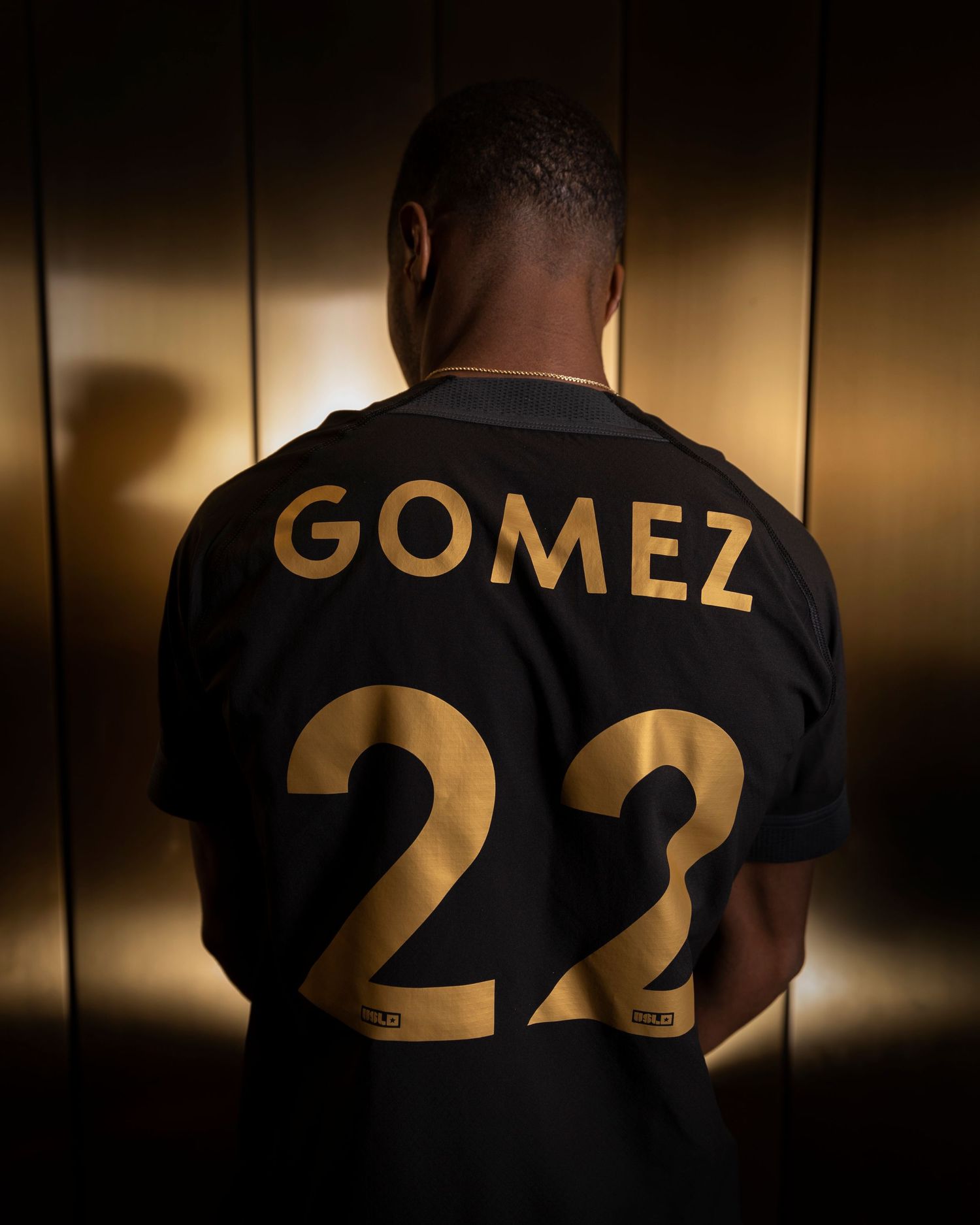 Black jersey with gold Gomez 22 lettering shown from behind.