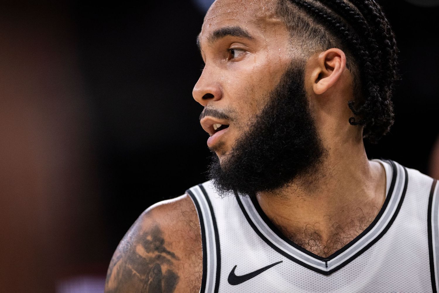 Close-up of player in black and white Spurs jersey during basketball game.