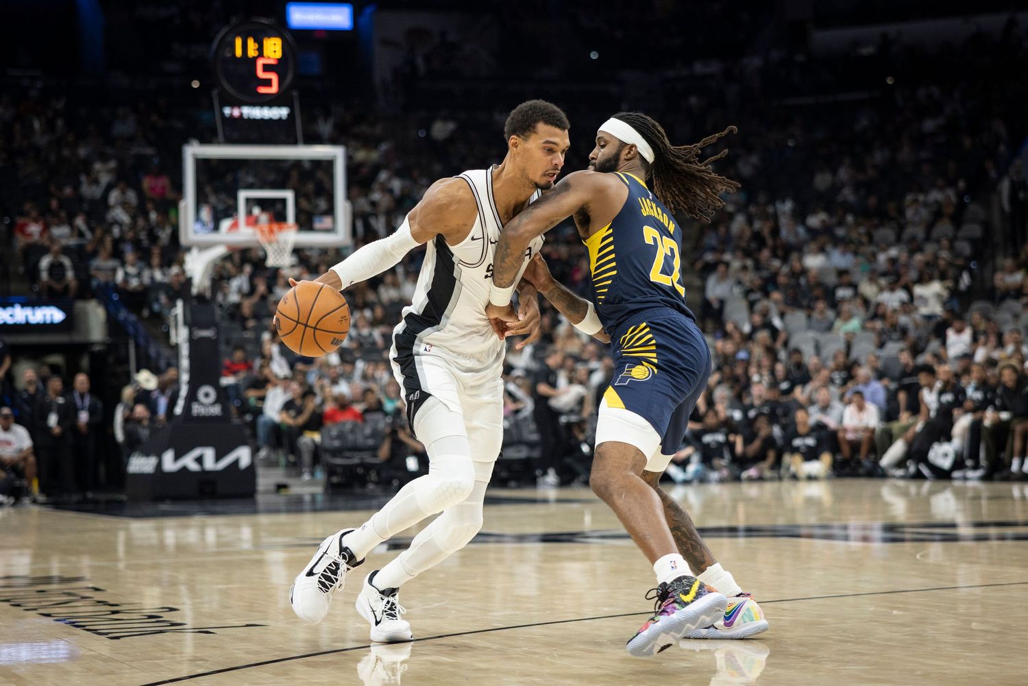 Two NBA players battle for position during a Spurs versus Pacers basketball game.