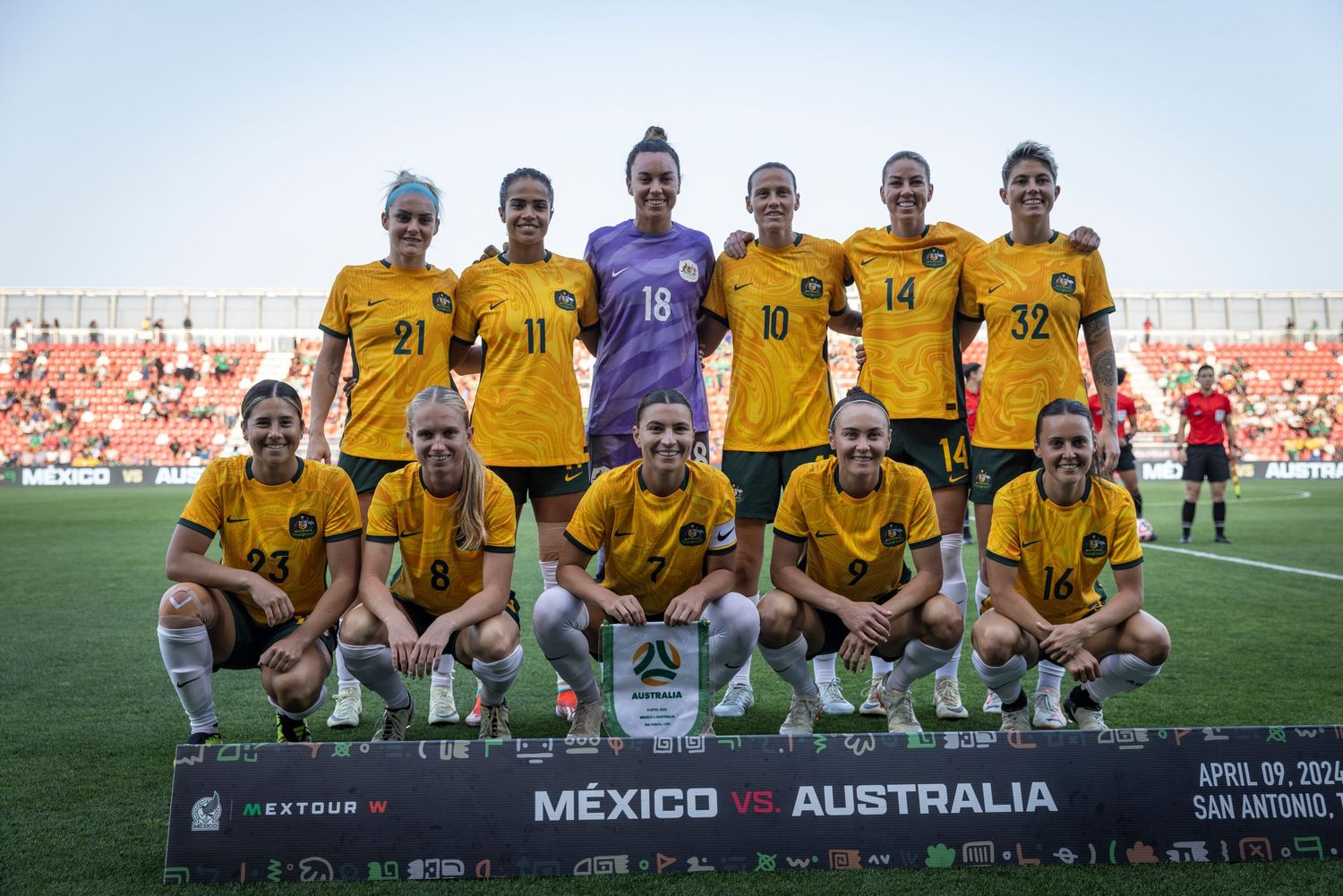 Australian national soccer team poses for official match photo in yellow uniforms.