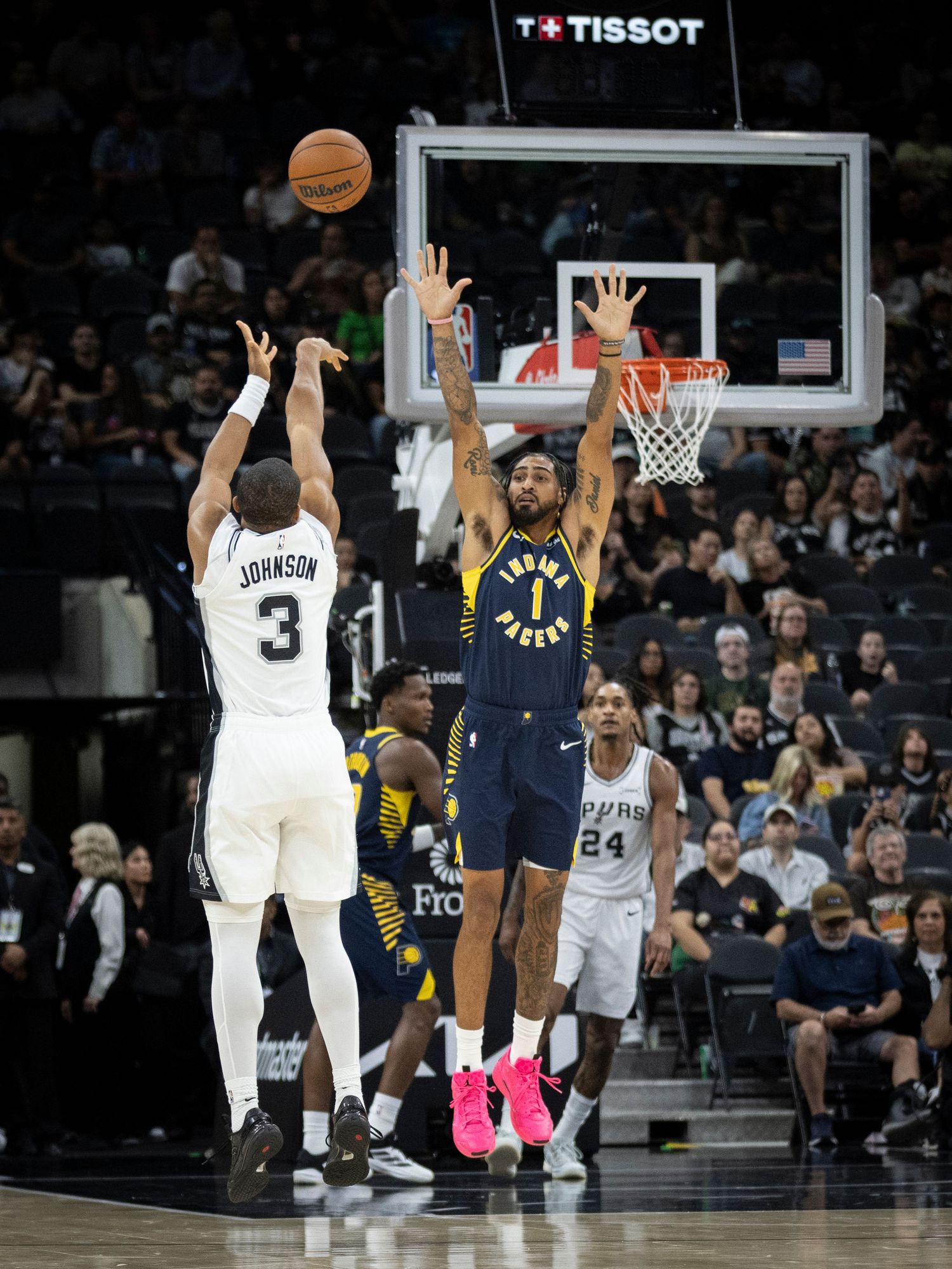 NBA players from the Spurs and Pacers jump for the ball during a competitive basketball game.