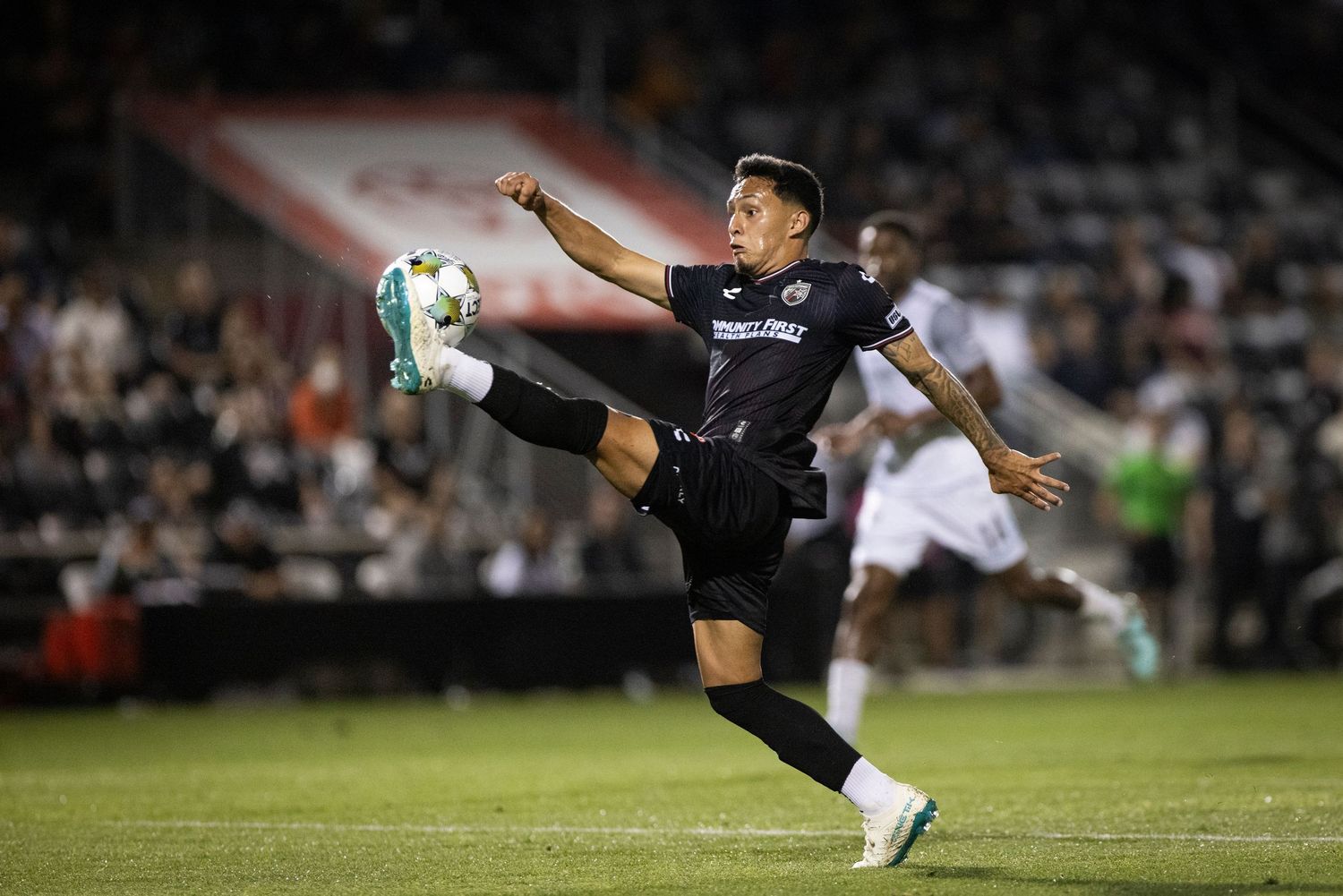 Soccer player performs acrobatic kick during nighttime match.