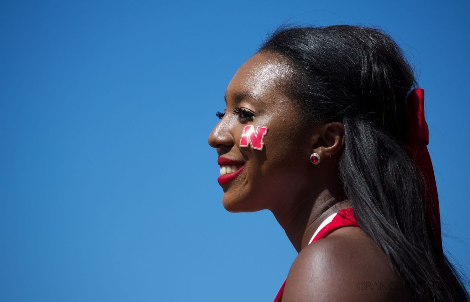 Athlete with red flower accessories posing against bright blue sky background.