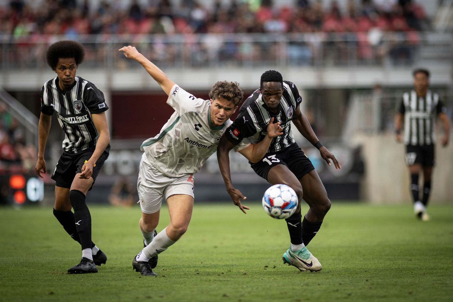 Soccer players from opposing teams battle for possession of the ball during an intense match.