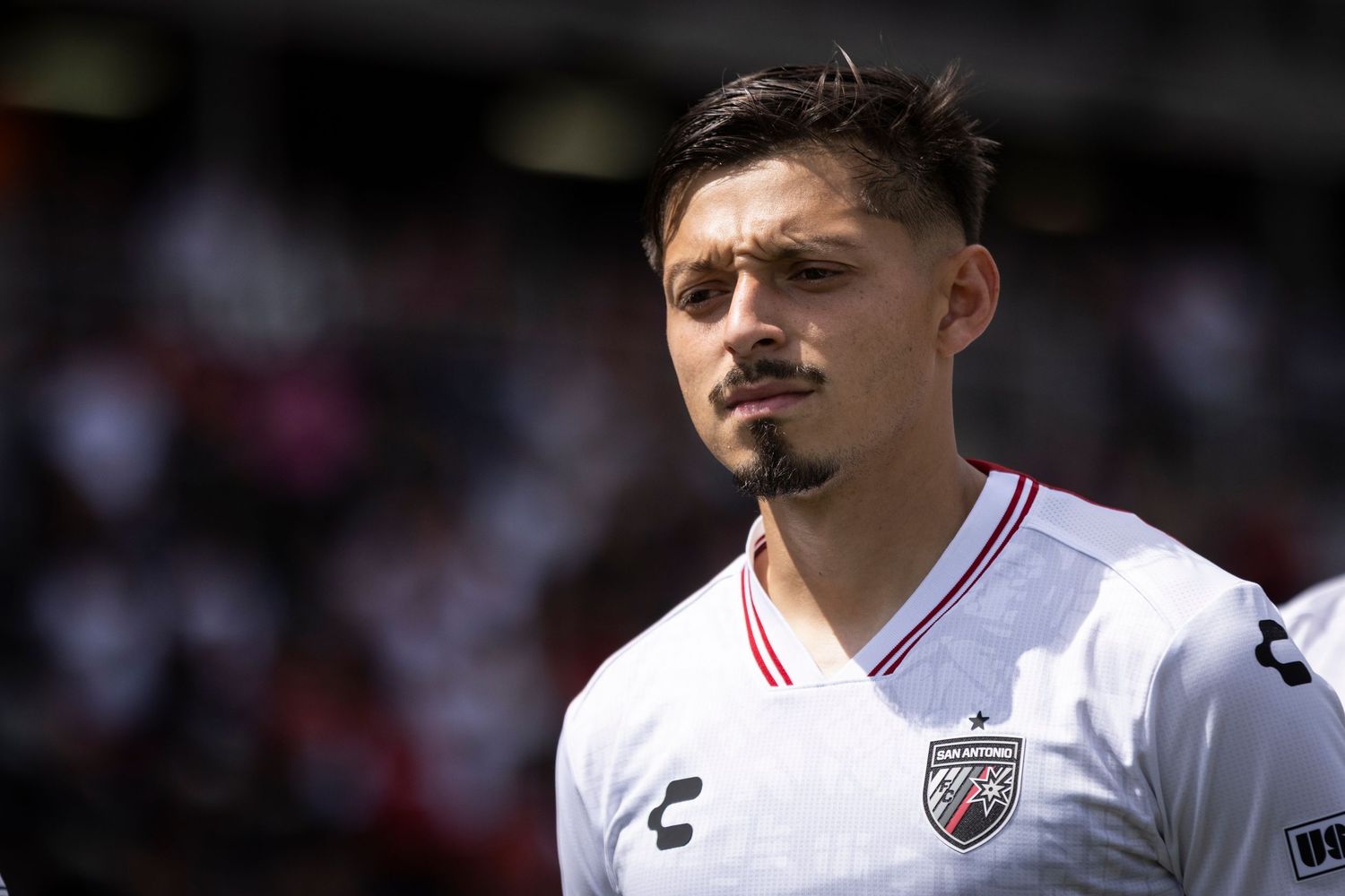 Close-up portrait of soccer player in white Chichupa uniform looking focused before match.