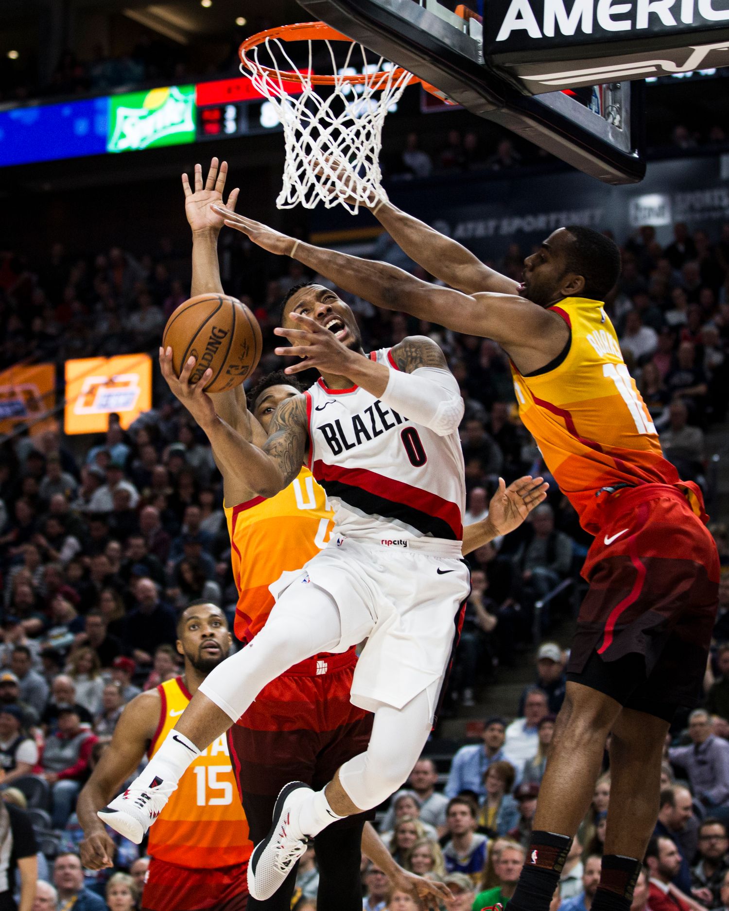 Basketball player drives to the hoop against defenders during professional game.