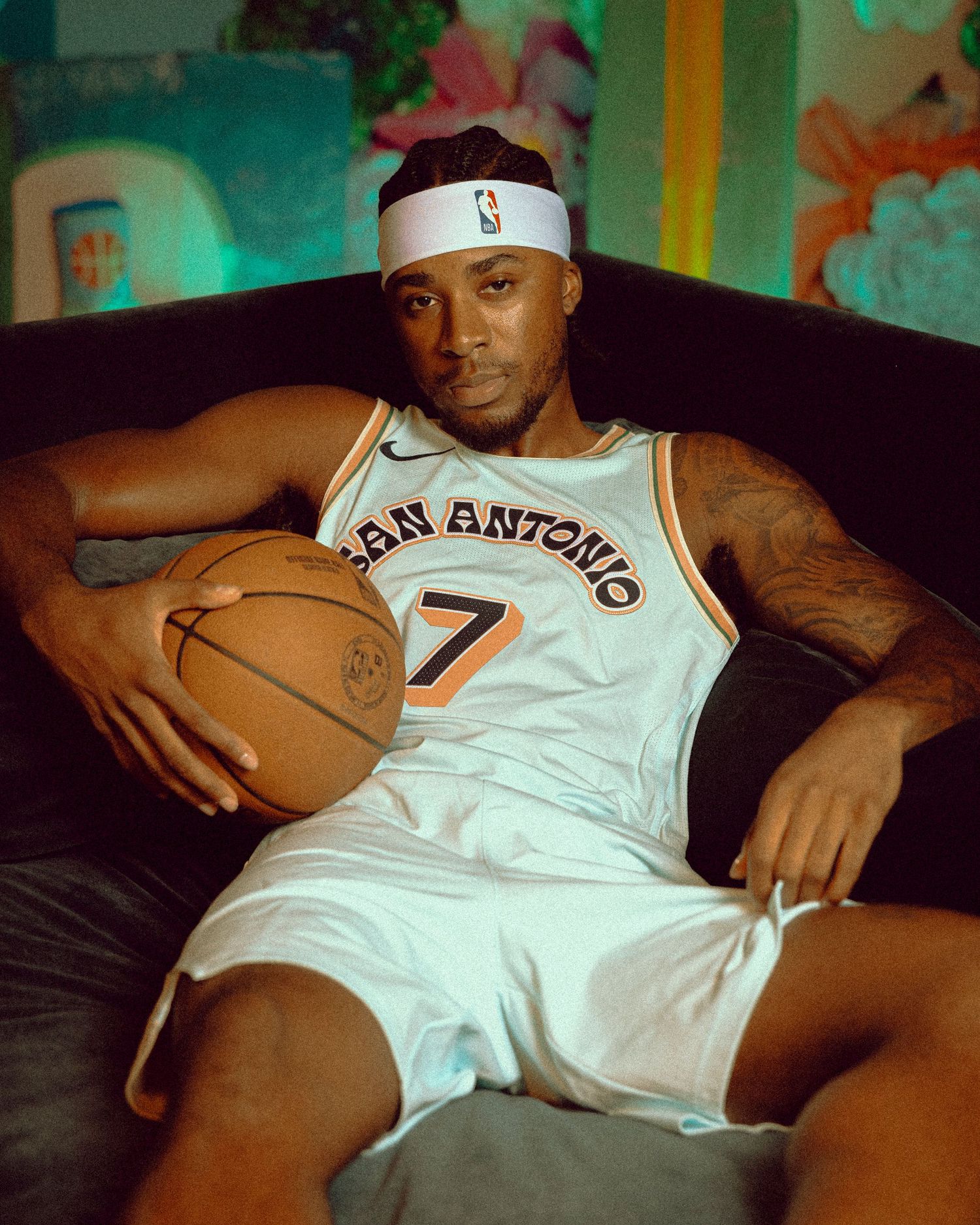 Basketball player in San Antonio number 7 jersey relaxes on couch with ball.