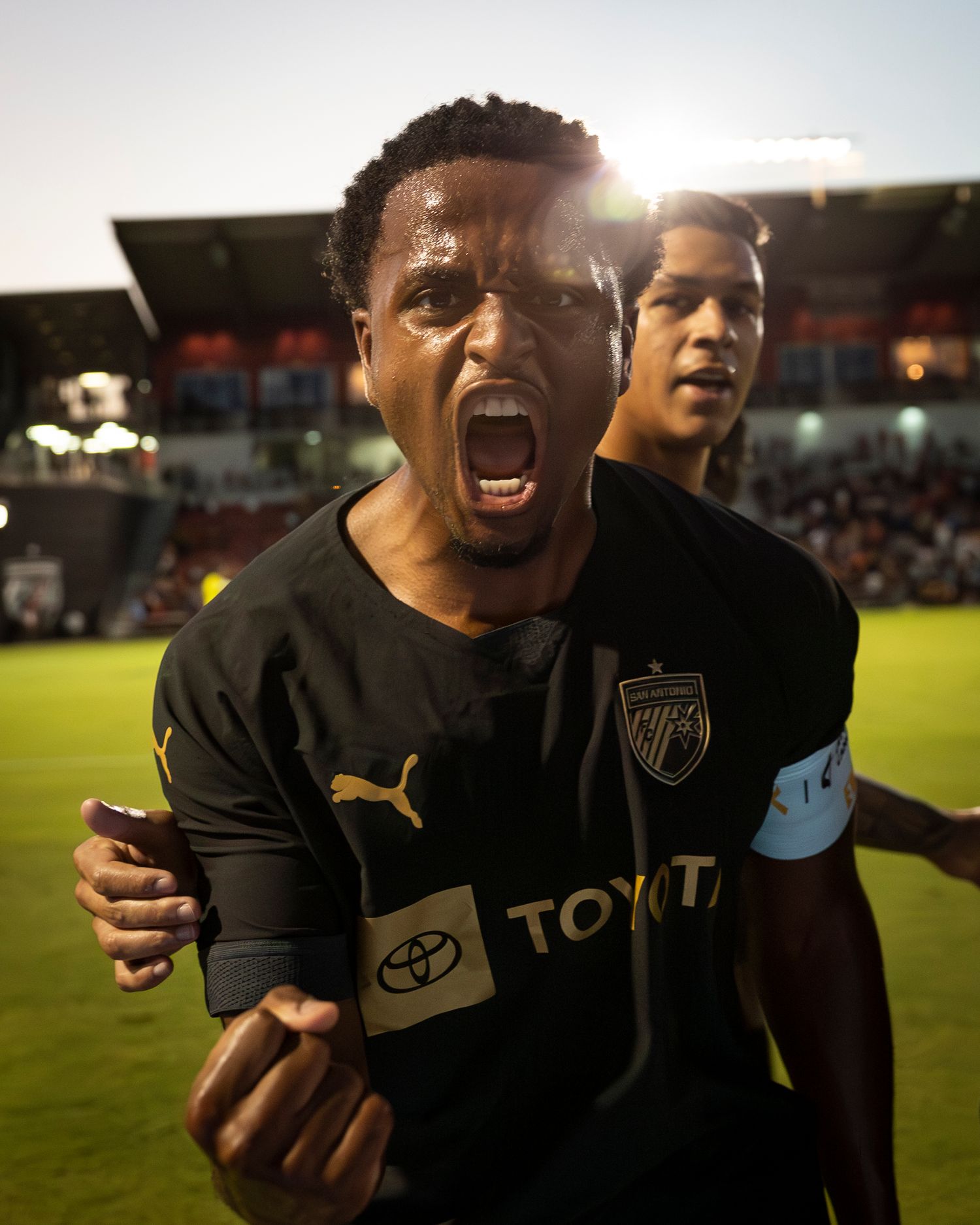 Passionate player celebrates on soccer field after match in black team uniform.