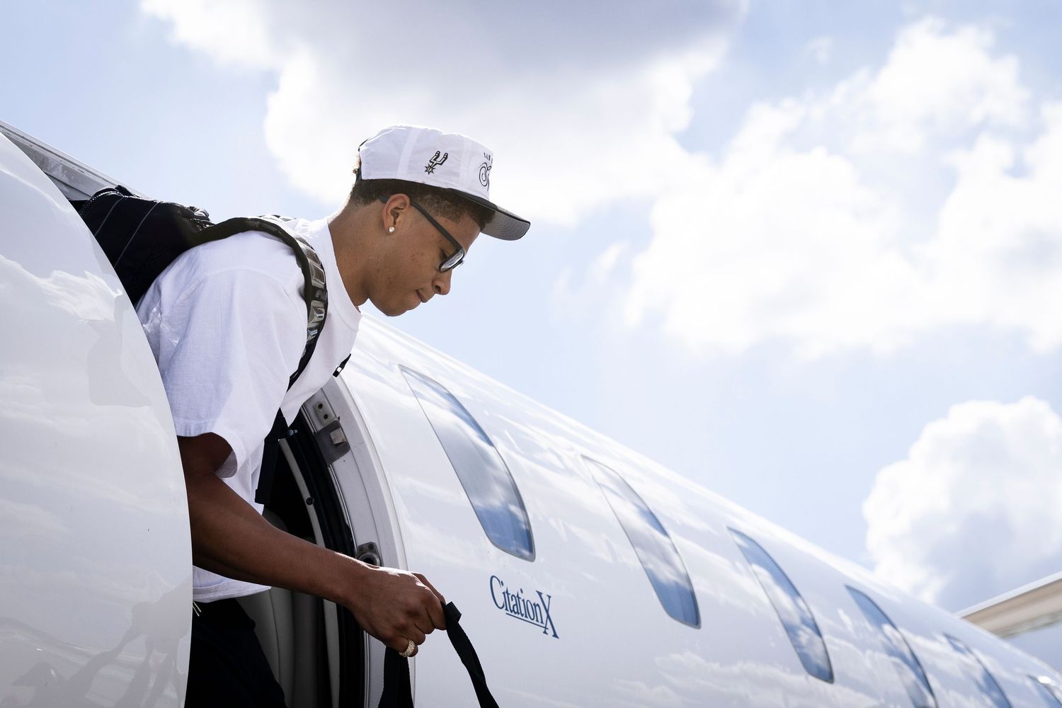 Airline ground crew member in white uniform inspecting and preparing a commercial aircraft on the tarmac.