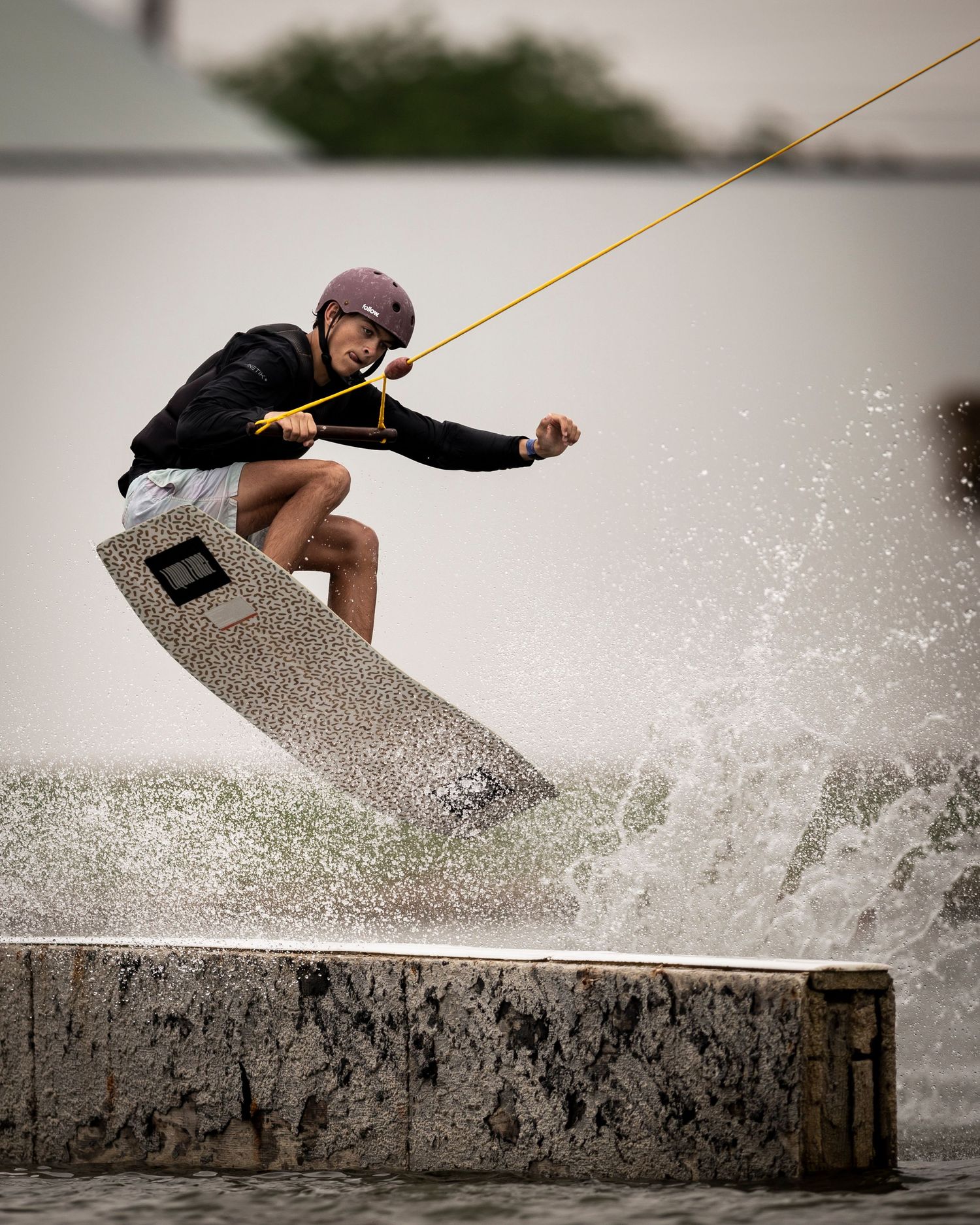 Wakeboarder performing aerial trick over wake with dramatic water spray.