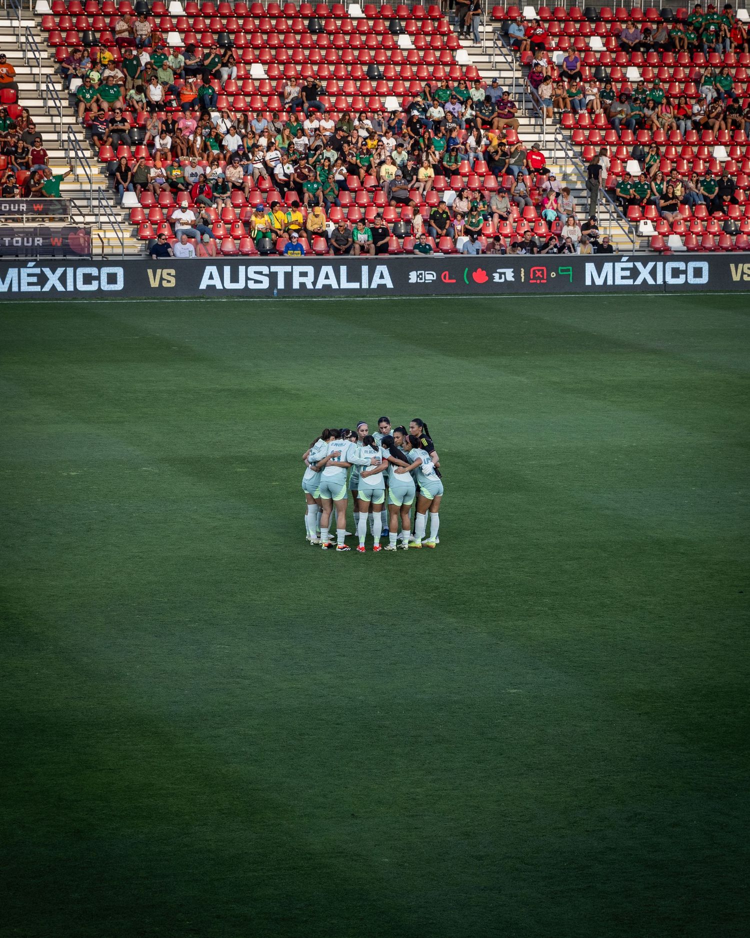 Soccer team huddles on field before Mexico vs Australia match.